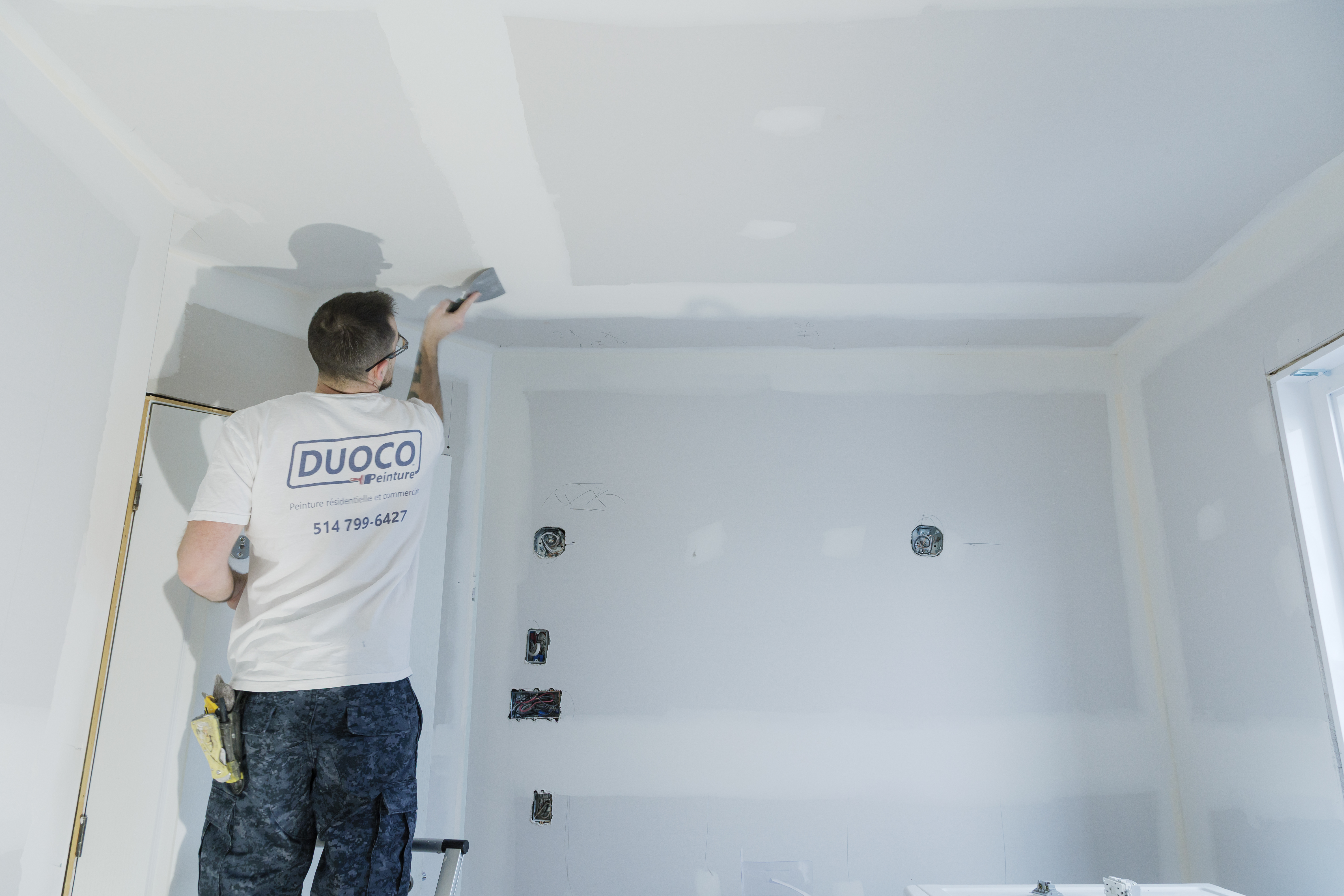 Worker applying joint compound on a drywall ceiling during interior renovations