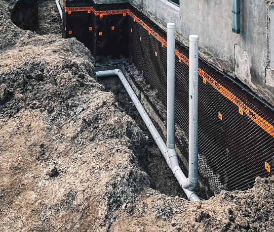 Travaux d’excavation pour l’installation d’un drain français et d’une membrane d’étanchéité sur les fondations d’une maison.