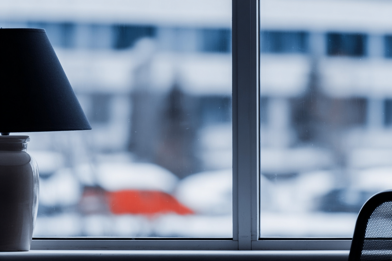 Indoor window with table lamp and blurred view of snowy buildings outside