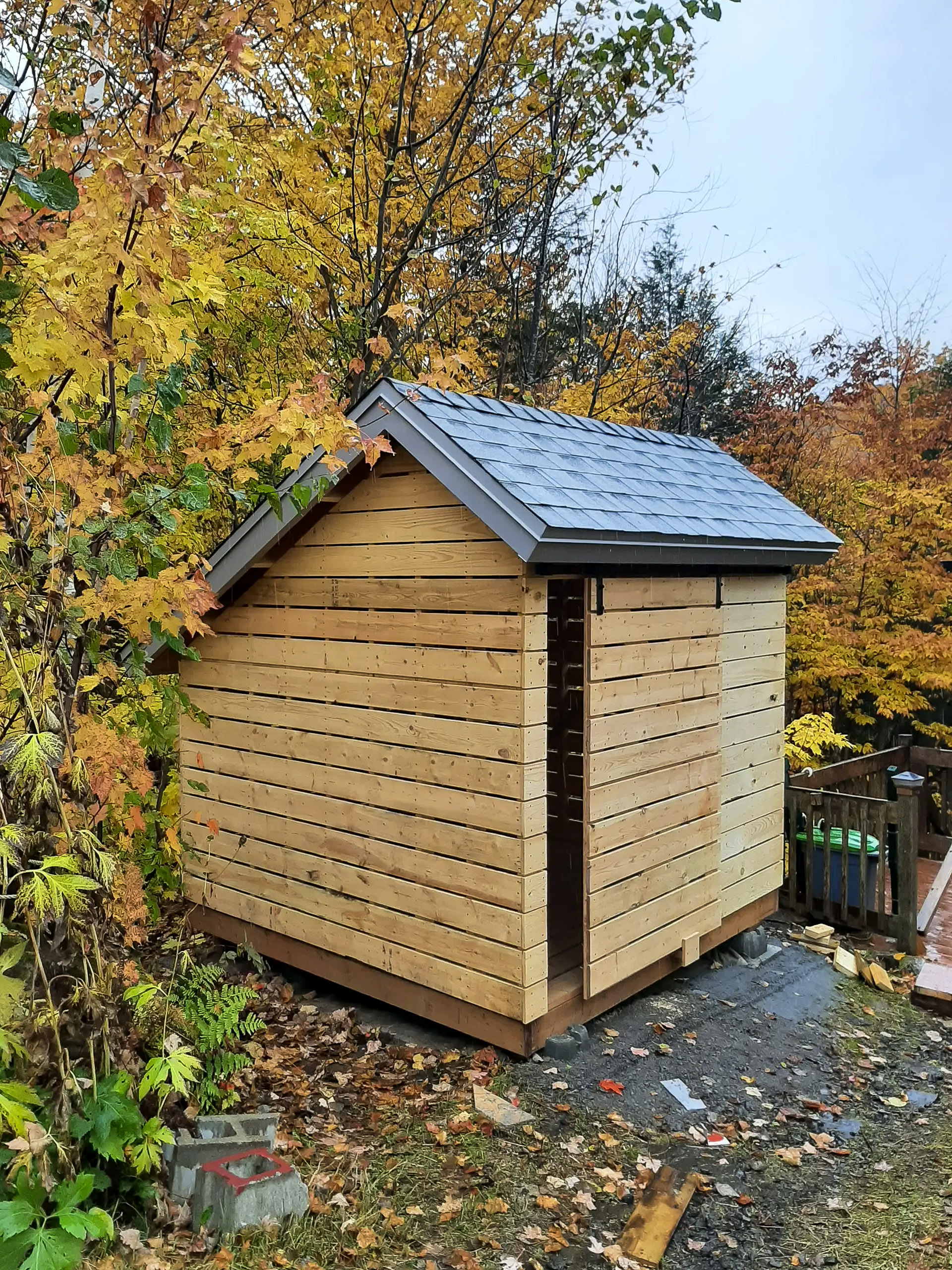 Natural wood shed under construction in a forested area during autumn