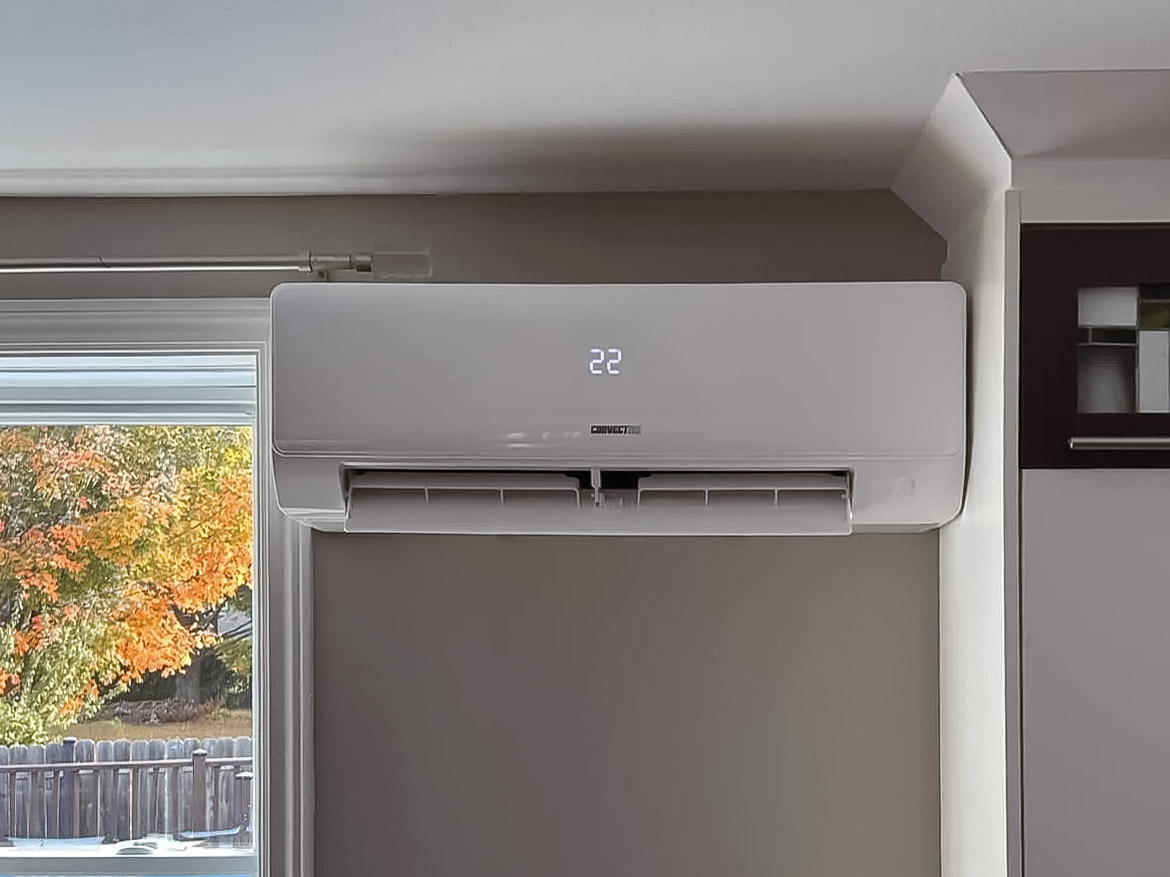 Wall-mounted air conditioner with a digital display showing 22 degrees in a residential home.