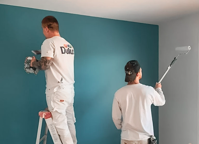 Travaux de peinture intérieure réalisés par des peintres professionnels appliquant une peinture bleue sur un mur pour une rénovation moderne.