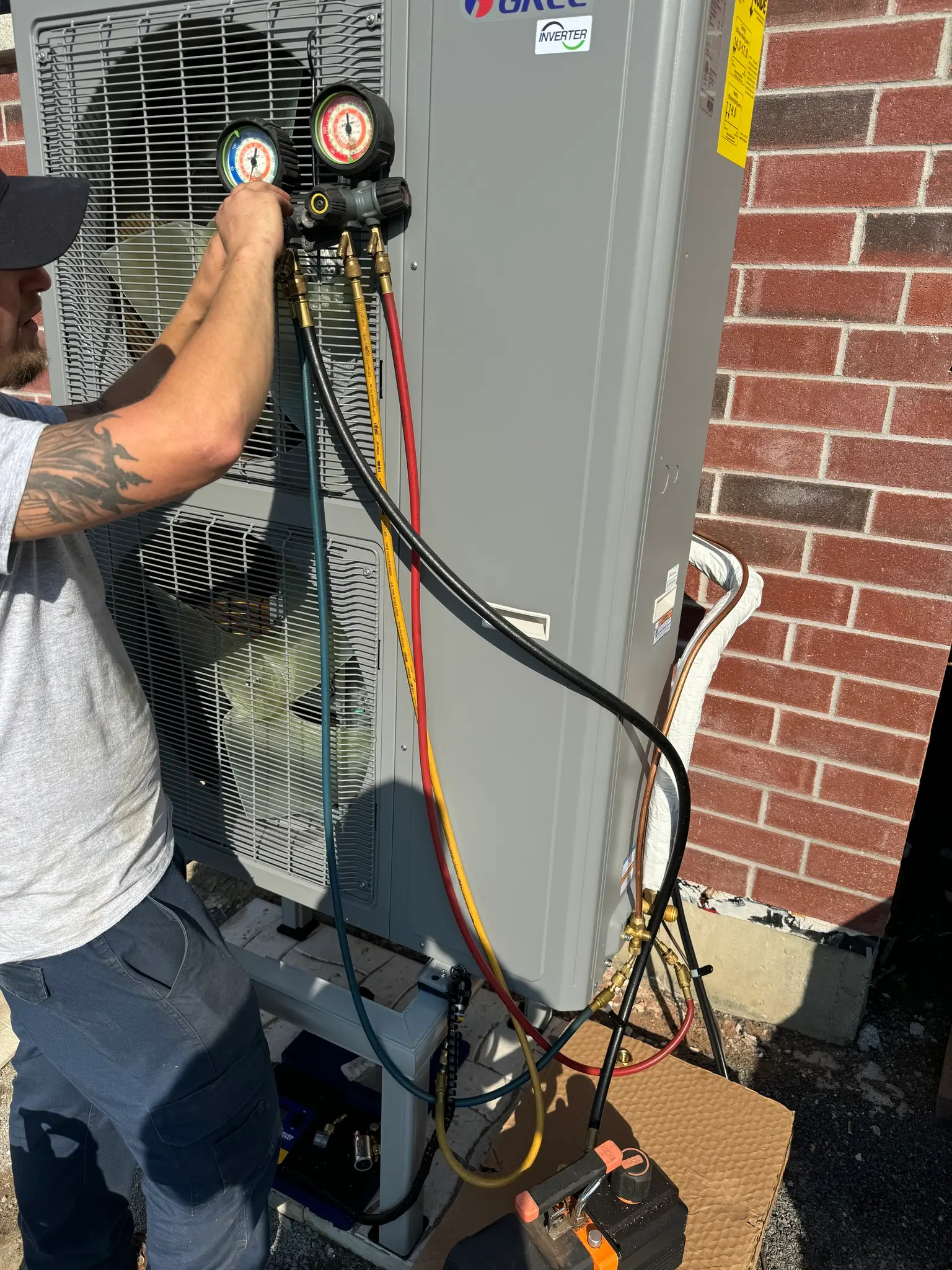 Technicien HVAC vérifiant la pression d’une thermopompe extérieure avec des manomètres lors d’une installation résidentielle.