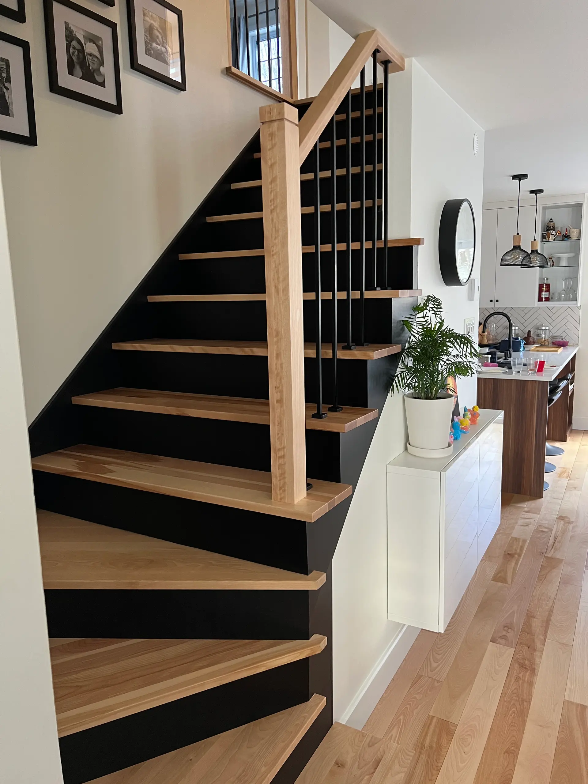 Escalier intérieur moderne en bois naturel avec contremarches noires, rampe métallique noire et aire ouverte lumineuse dans une résidence contemporaine 