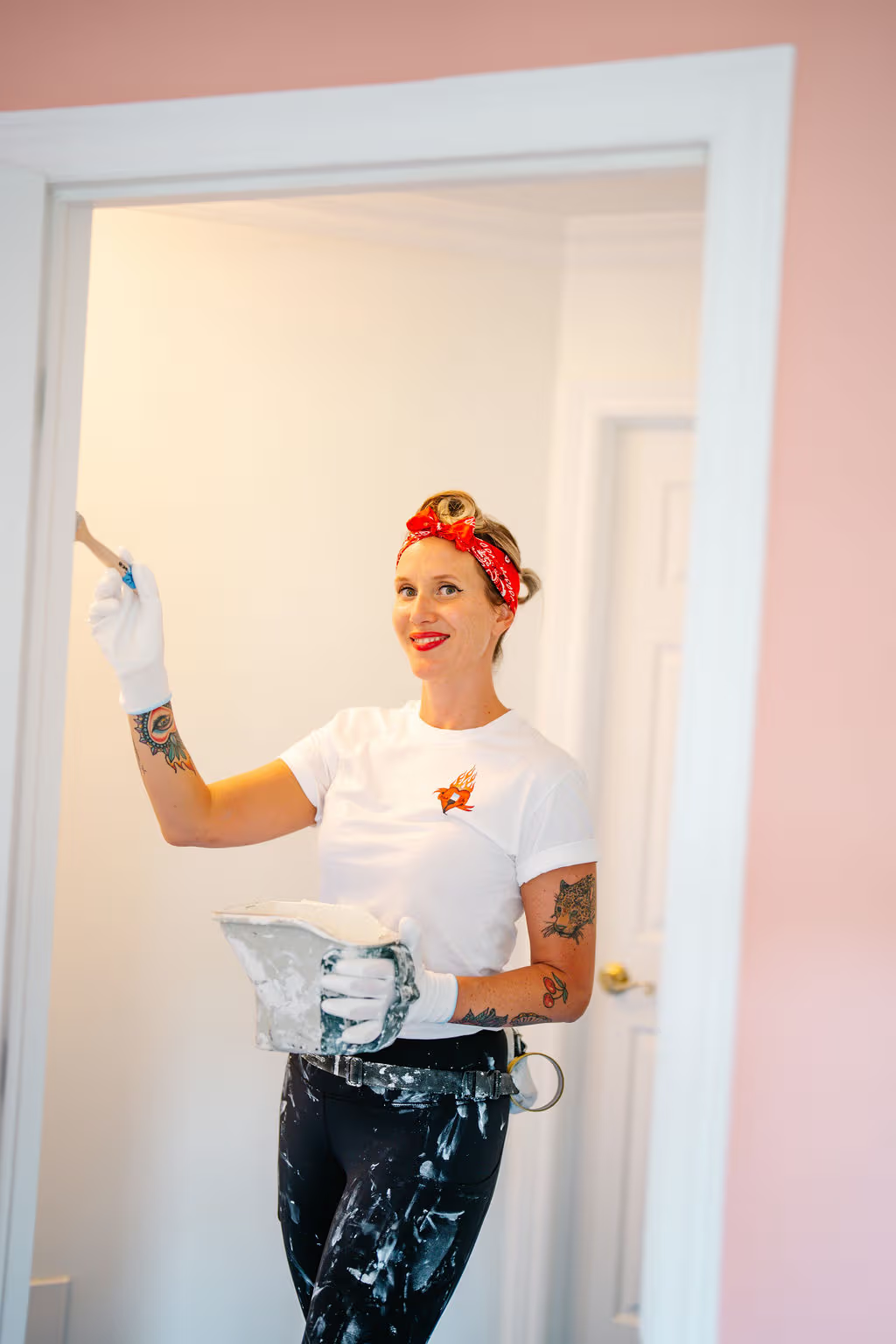 Professional painter applying white paint to an interior door frame in a bright residential room