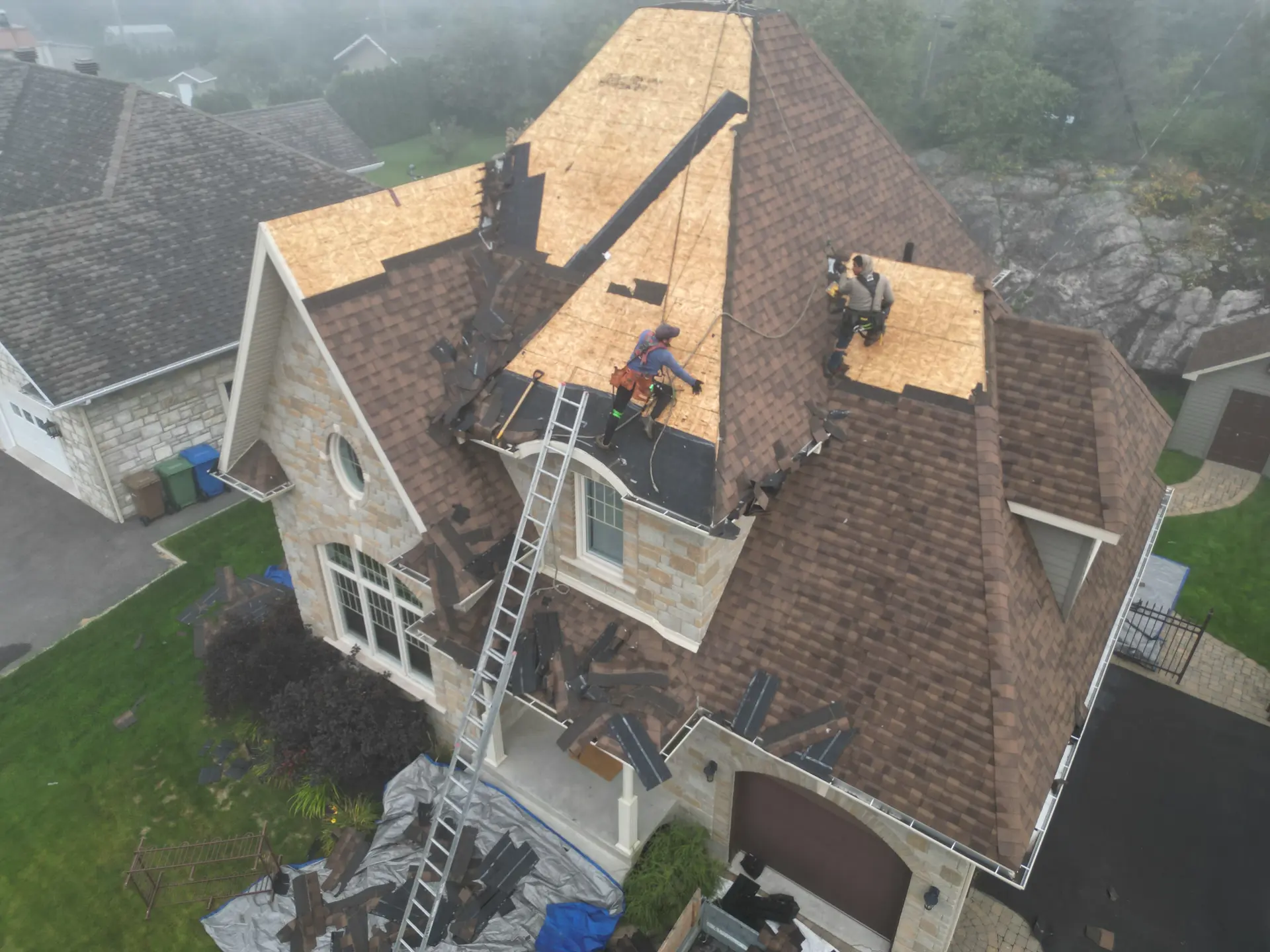 Renovation work on a residential roof with shingle replacement and new underlayment installation.