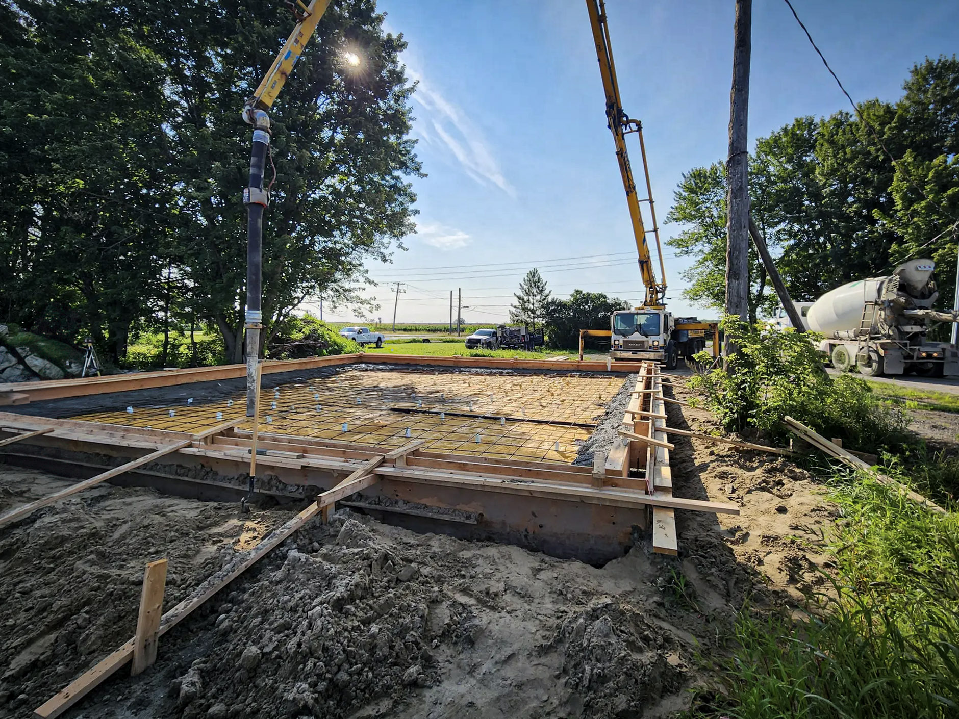 Coulage de béton pour la fondation d'une maison avec une pompe et un camion malaxeur.