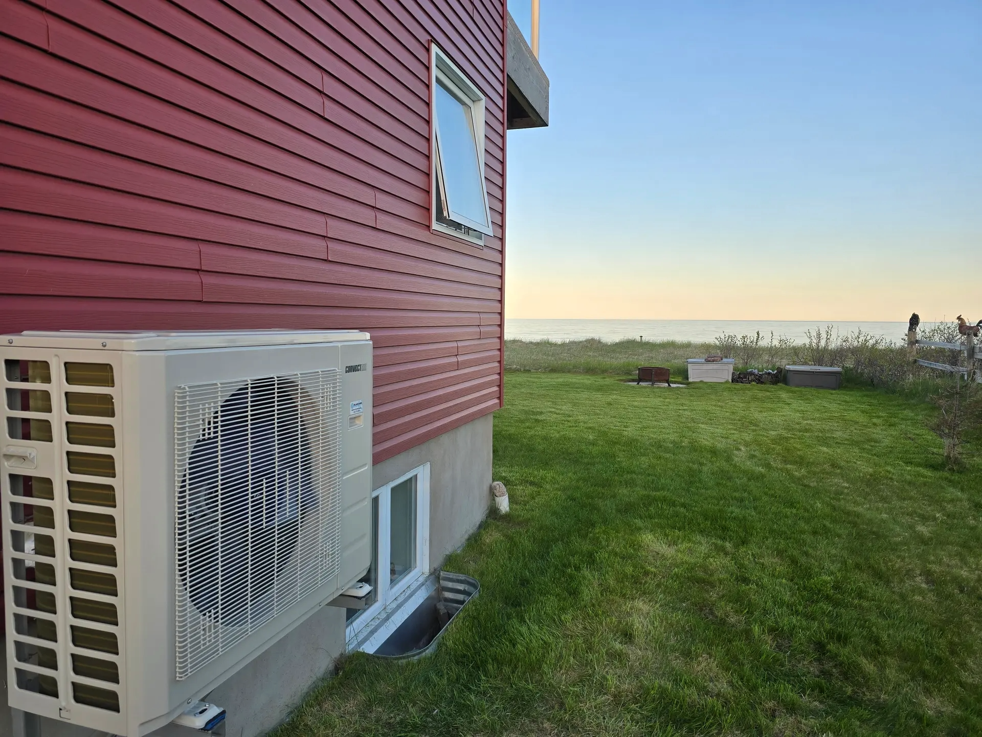 Samsung outdoor air conditioning unit with a fan, facing a lush garden and the ocean.