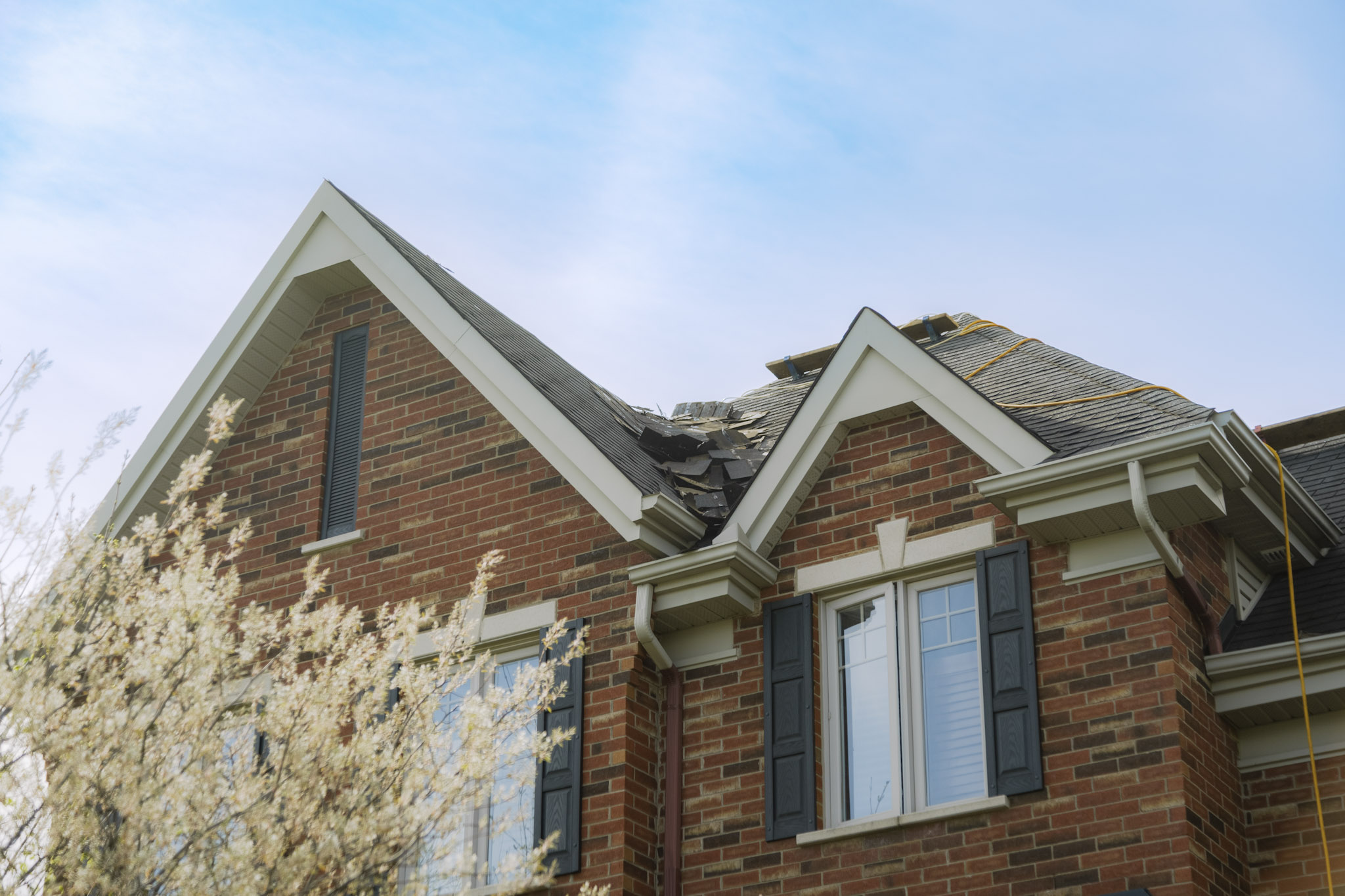 Toiture endommagée sur une maison en brique, en cours de réparation après des dégâts majeurs