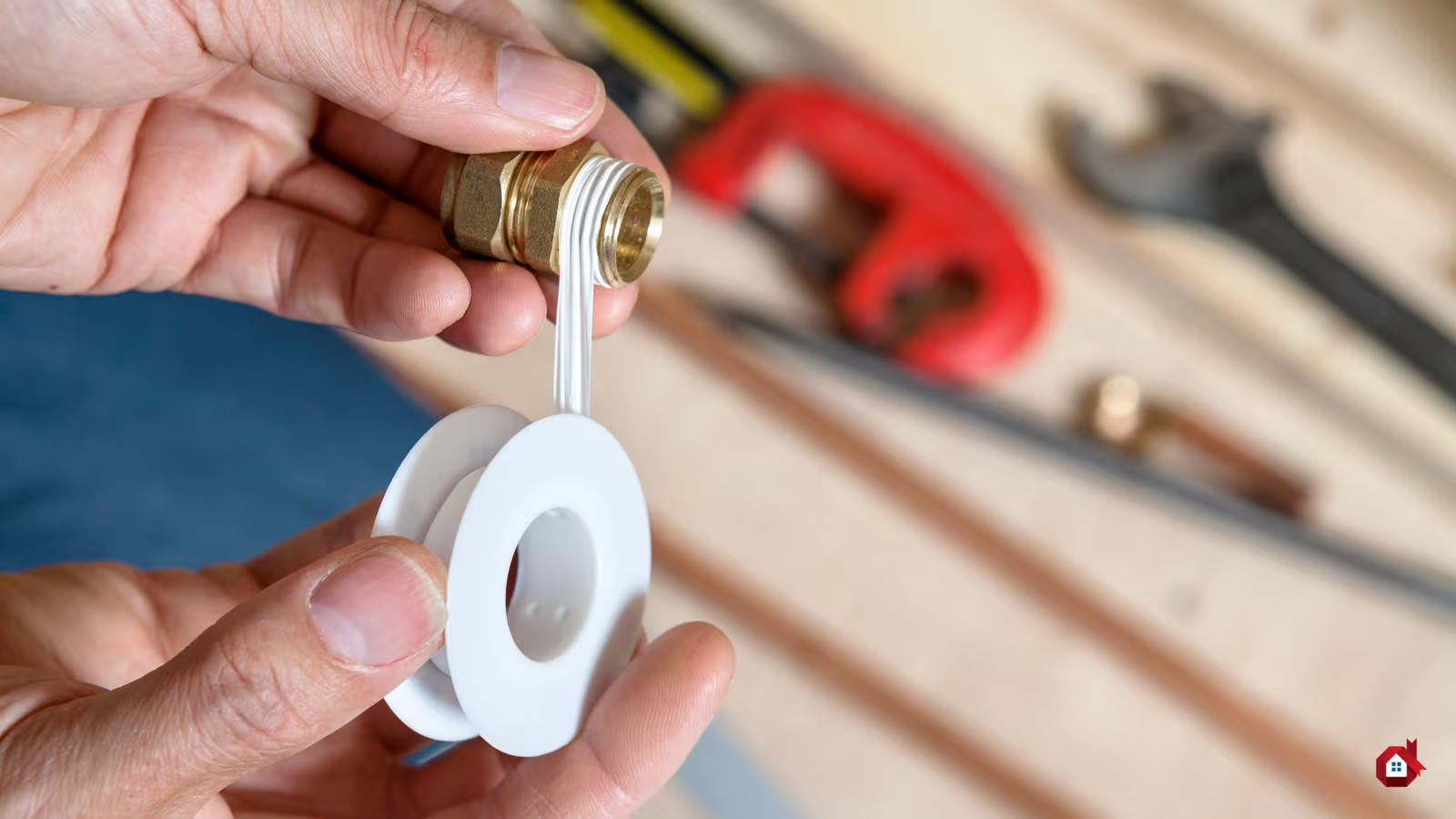 Mains appliquant du ruban de plomberie blanc sur un raccord en laiton avec outils de plomberie en arrière-plan.