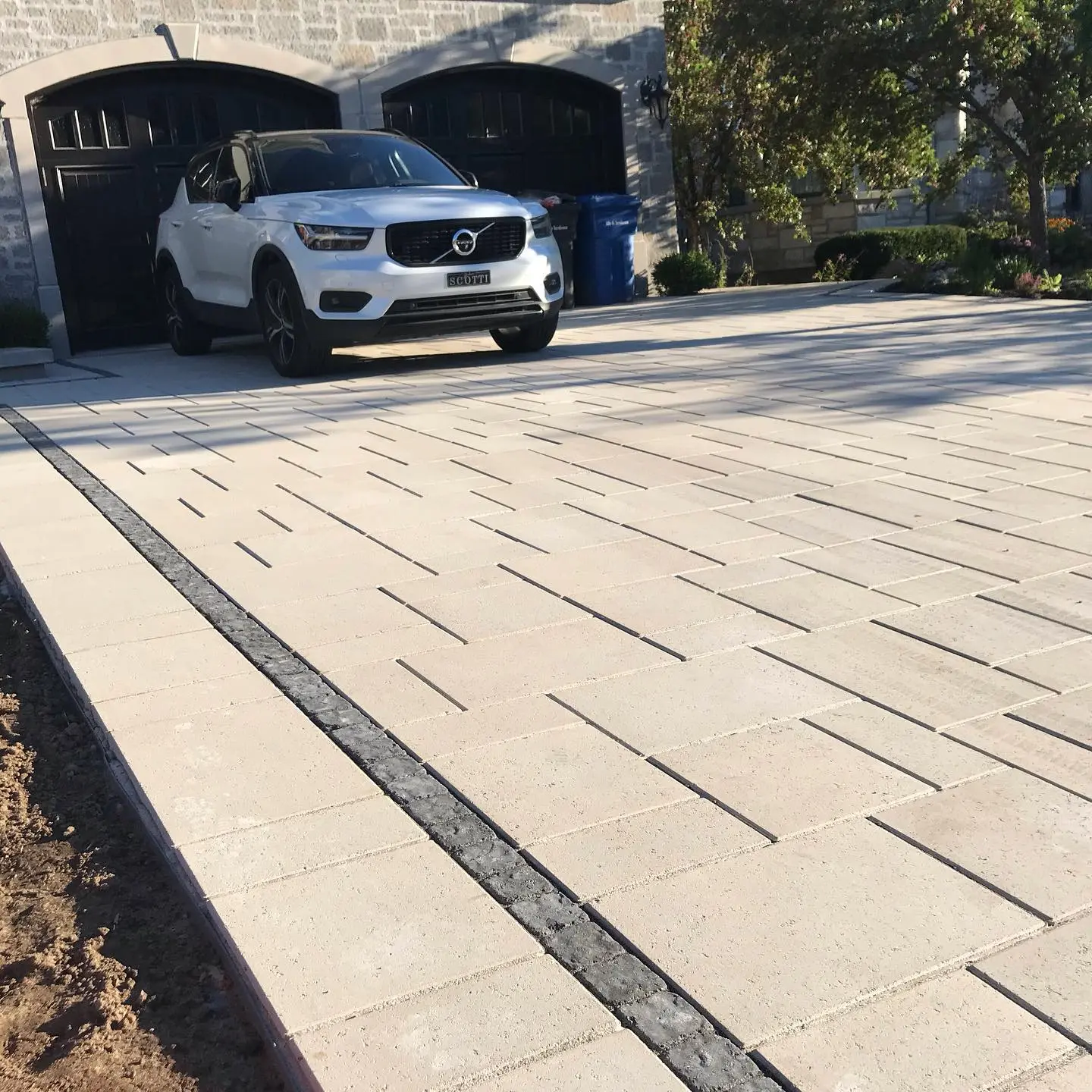 Residential driveway with beige interlocking pavers, linear accent design, and premium finish