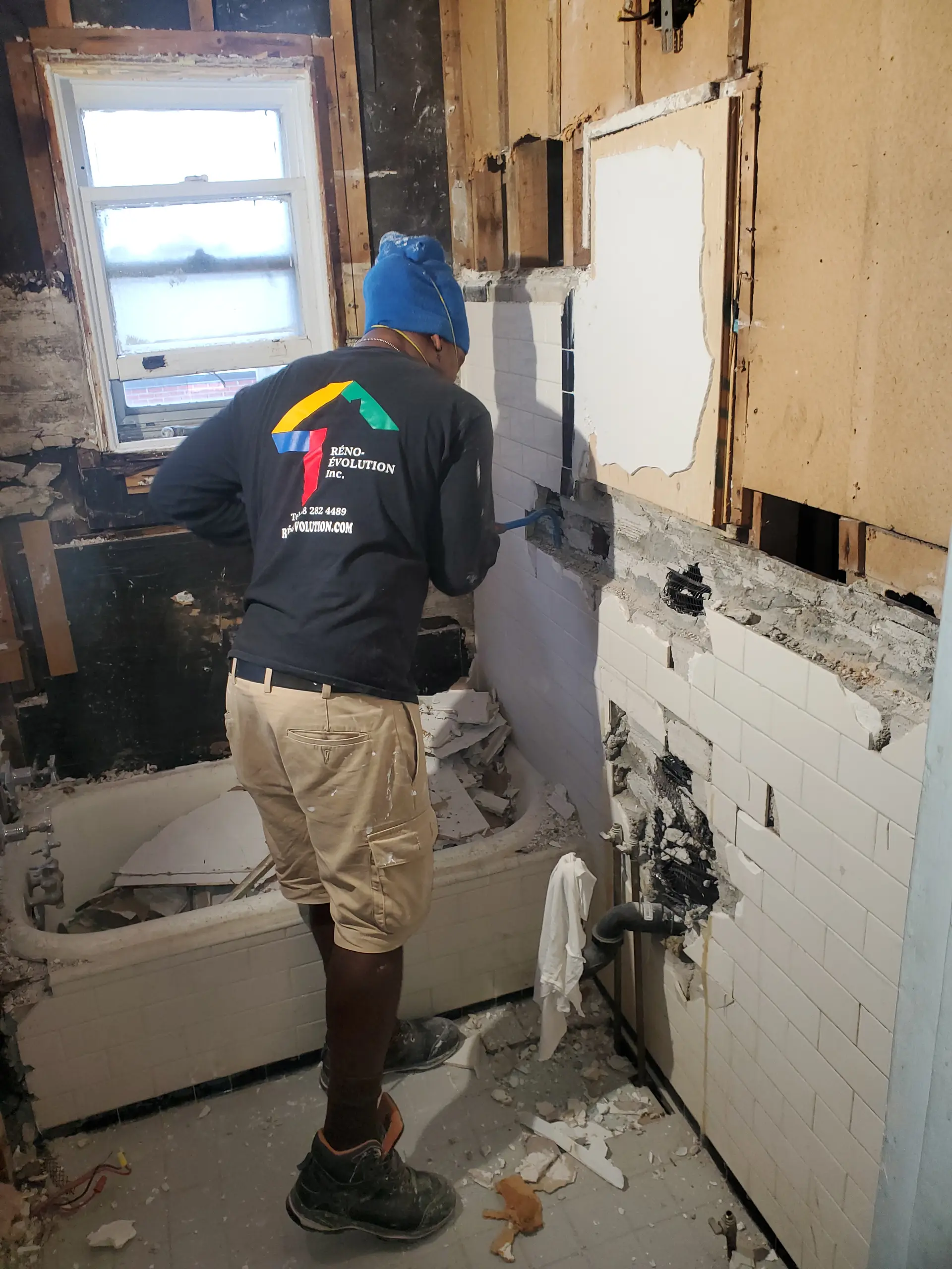 Bathroom demolition work with tile removal and exposed walls during renovation