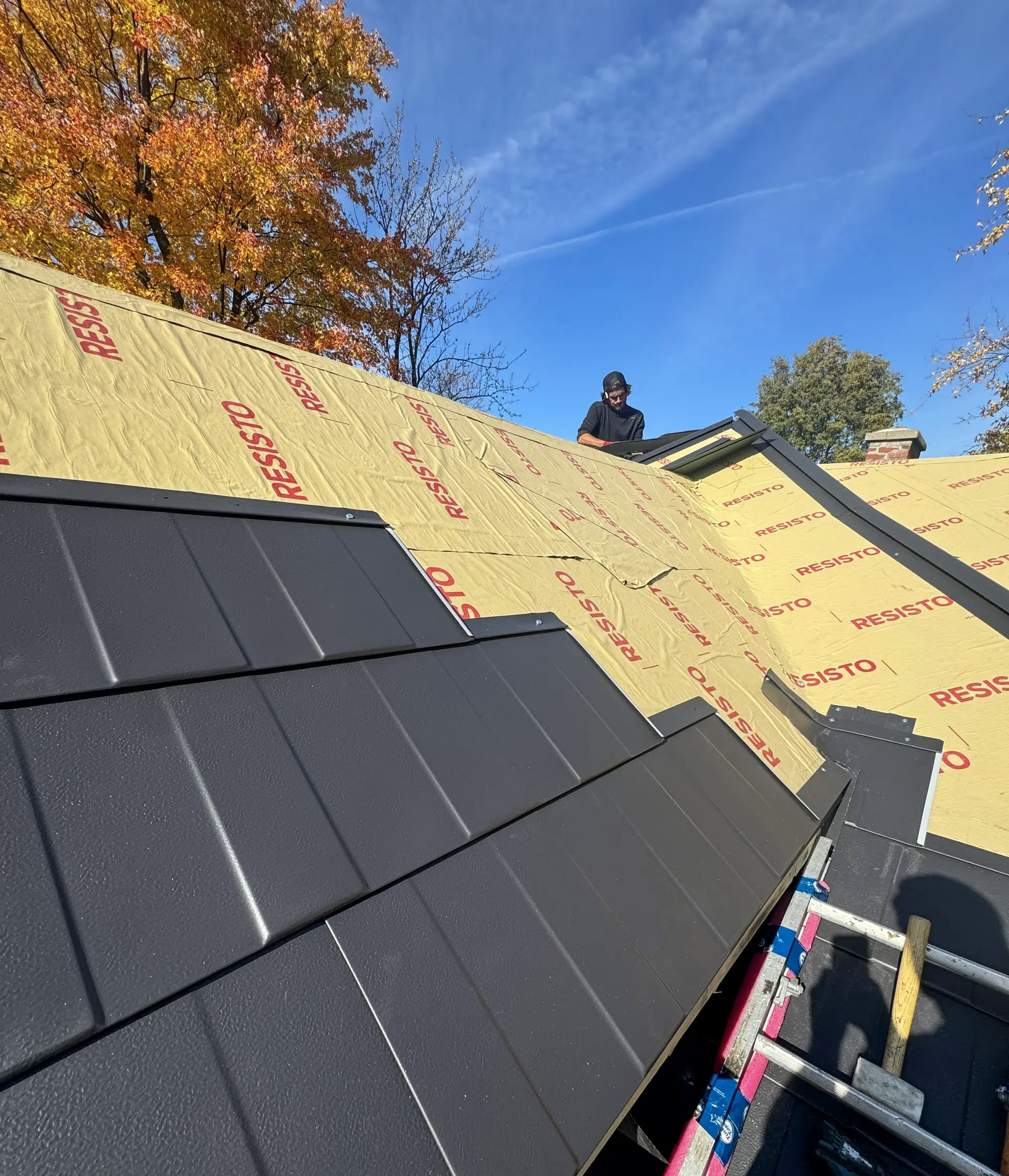 Installation d’une toiture en tôle noire avec sous-couche isolante Resisto sur une maison résidentielle en automne