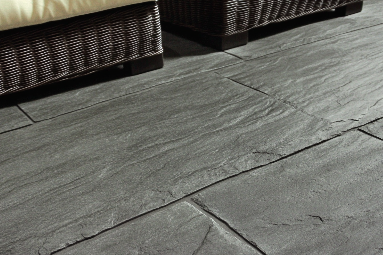 Sol en béton estampé gris foncé imitant l’ardoise avec surface texturée et joints rectangulaires, idéal pour terrasses ou vérandas
