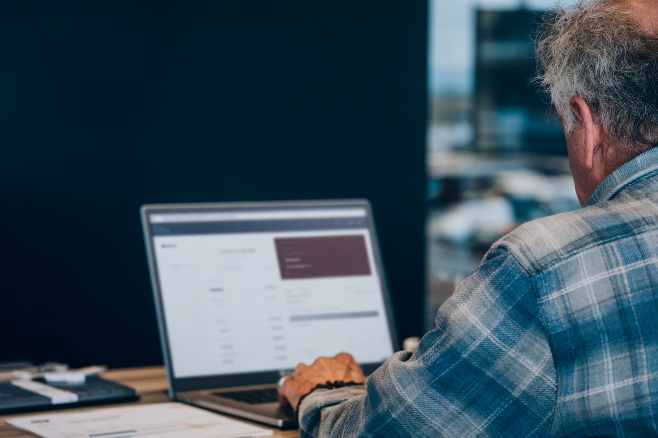 Senior male consultant using a management interface on a laptop in an office environment