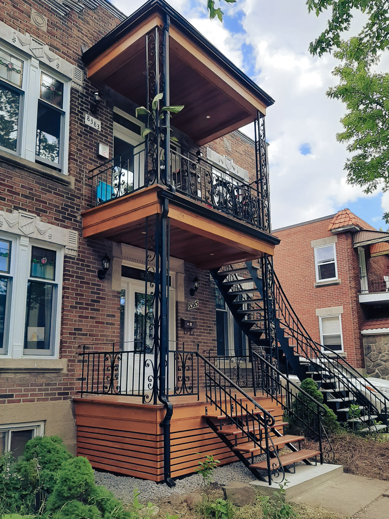 Montreal brick plex with renovated wooden balconies, black metal exterior stairs and decorative ornaments