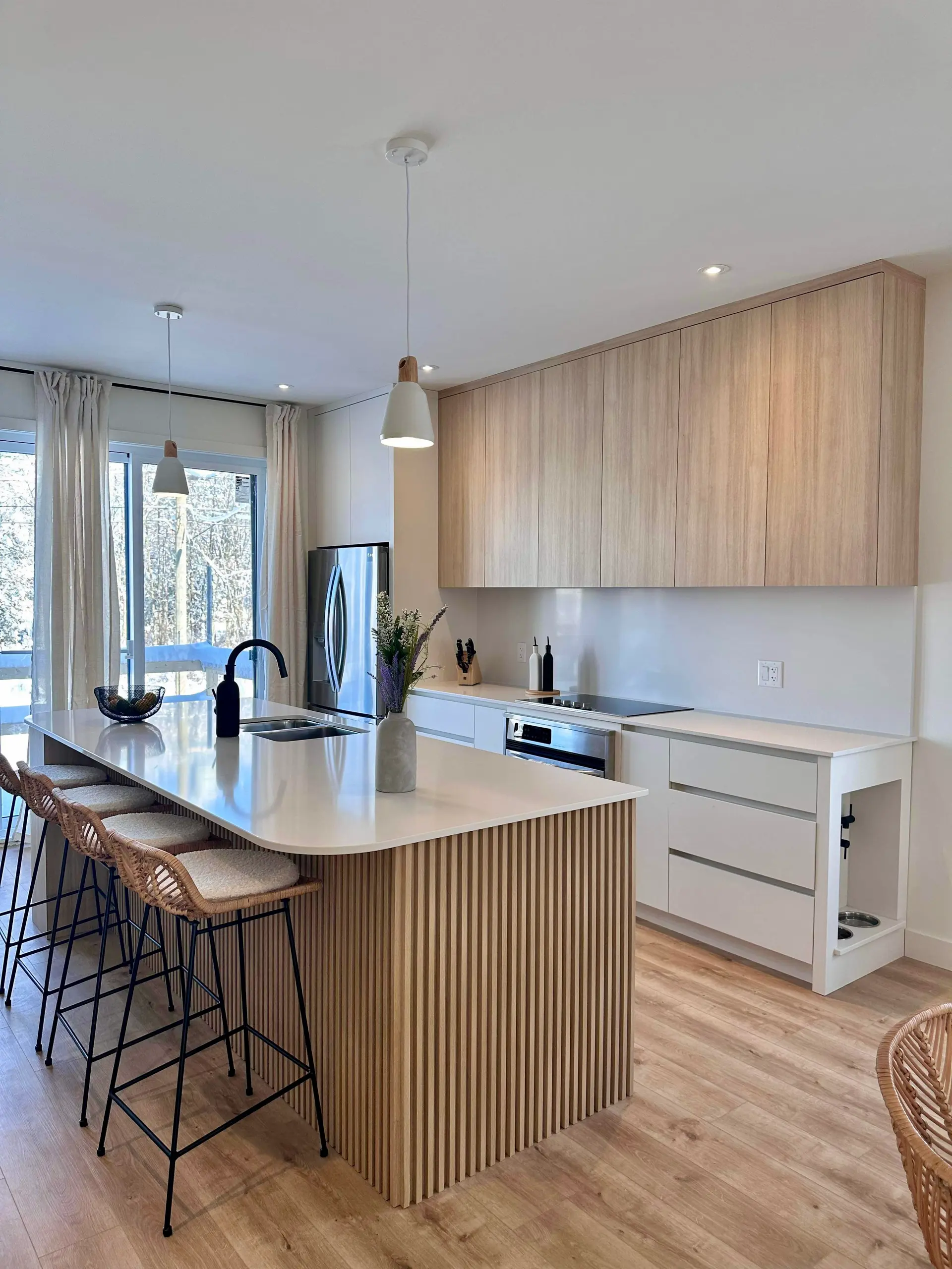 Modern kitchen with wooden island, white countertop, minimalist cabinets, and stainless steel appliances