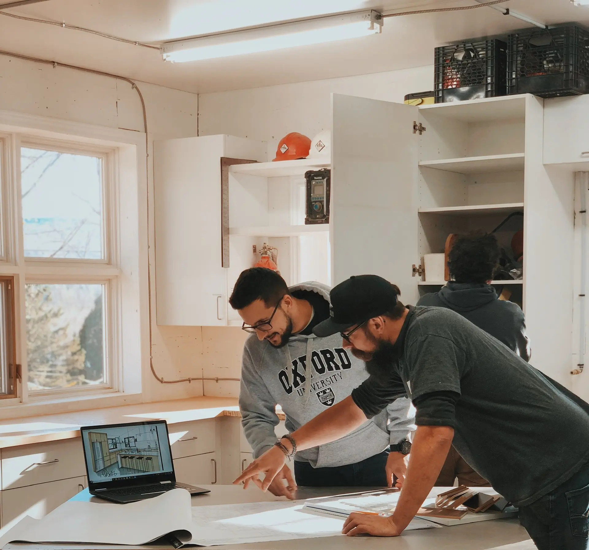 Professionals collaborating in a workshop on an architectural project design with plans and a laptop.
