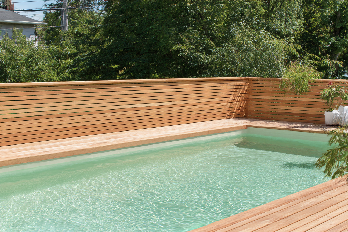 Inground pool with deck and natural wood fence with horizontal slats in a residential yard