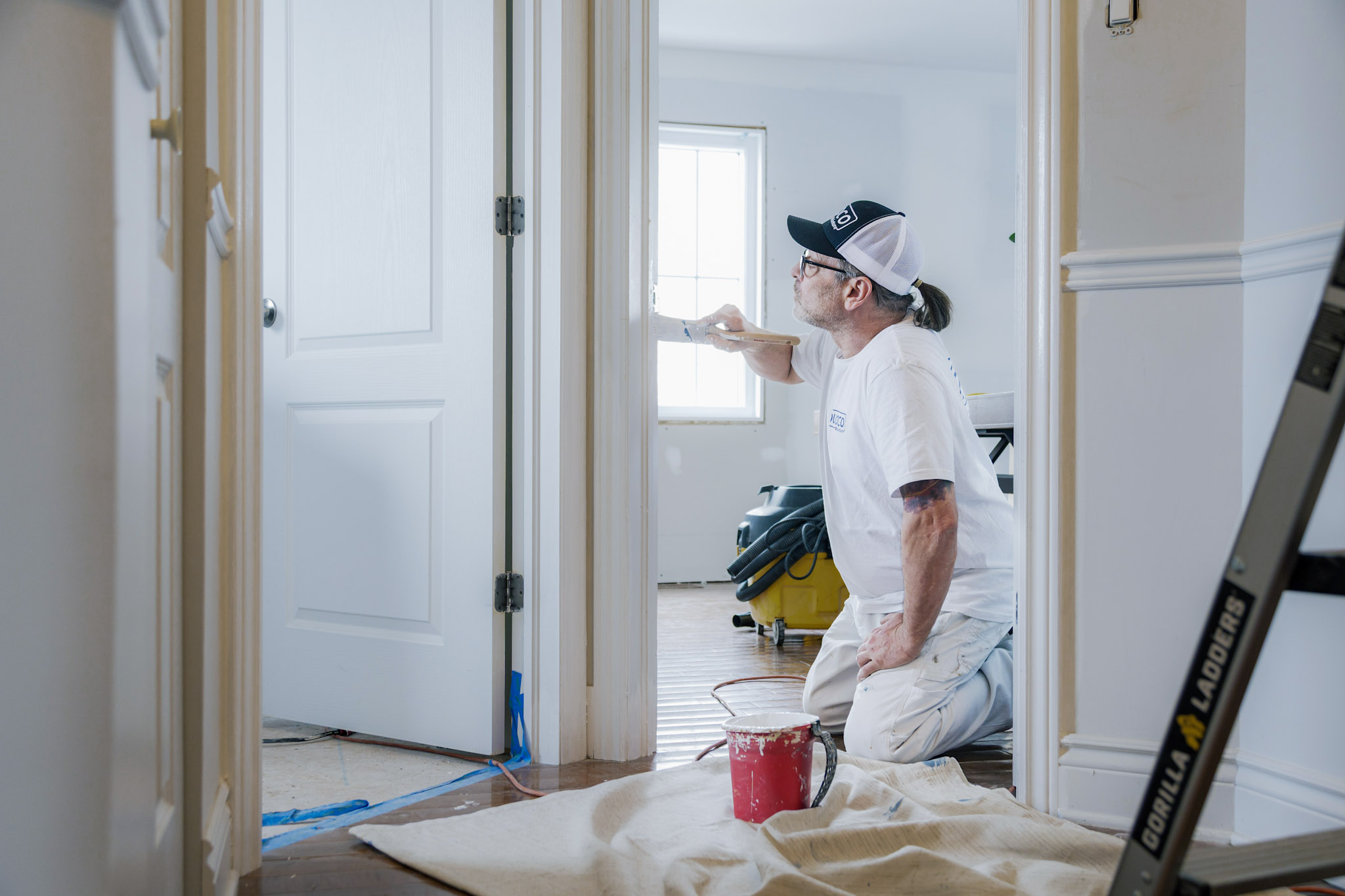 Peintre professionnel appliquant de la peinture blanche sur les murs d'une maison en rénovation intérieure