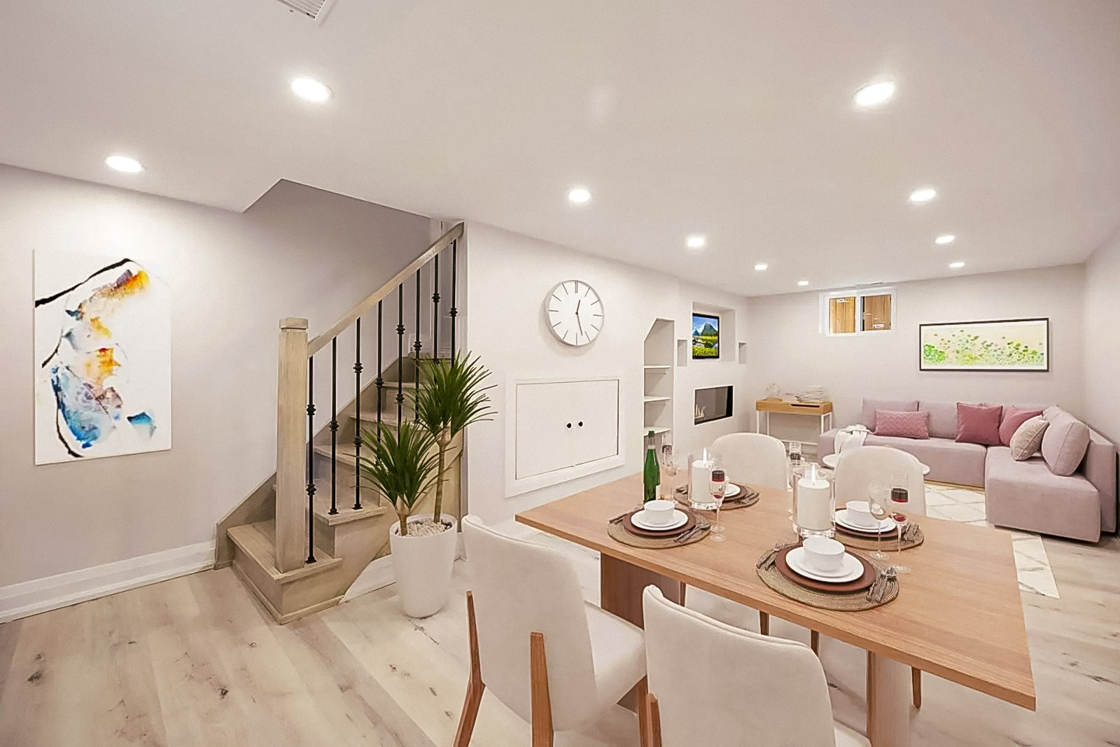 Sous-sol aménagé au style épuré avec salle à manger, escalier en bois clair, salon avec canapé rose pâle, et murs décorés d’œuvres modernes.