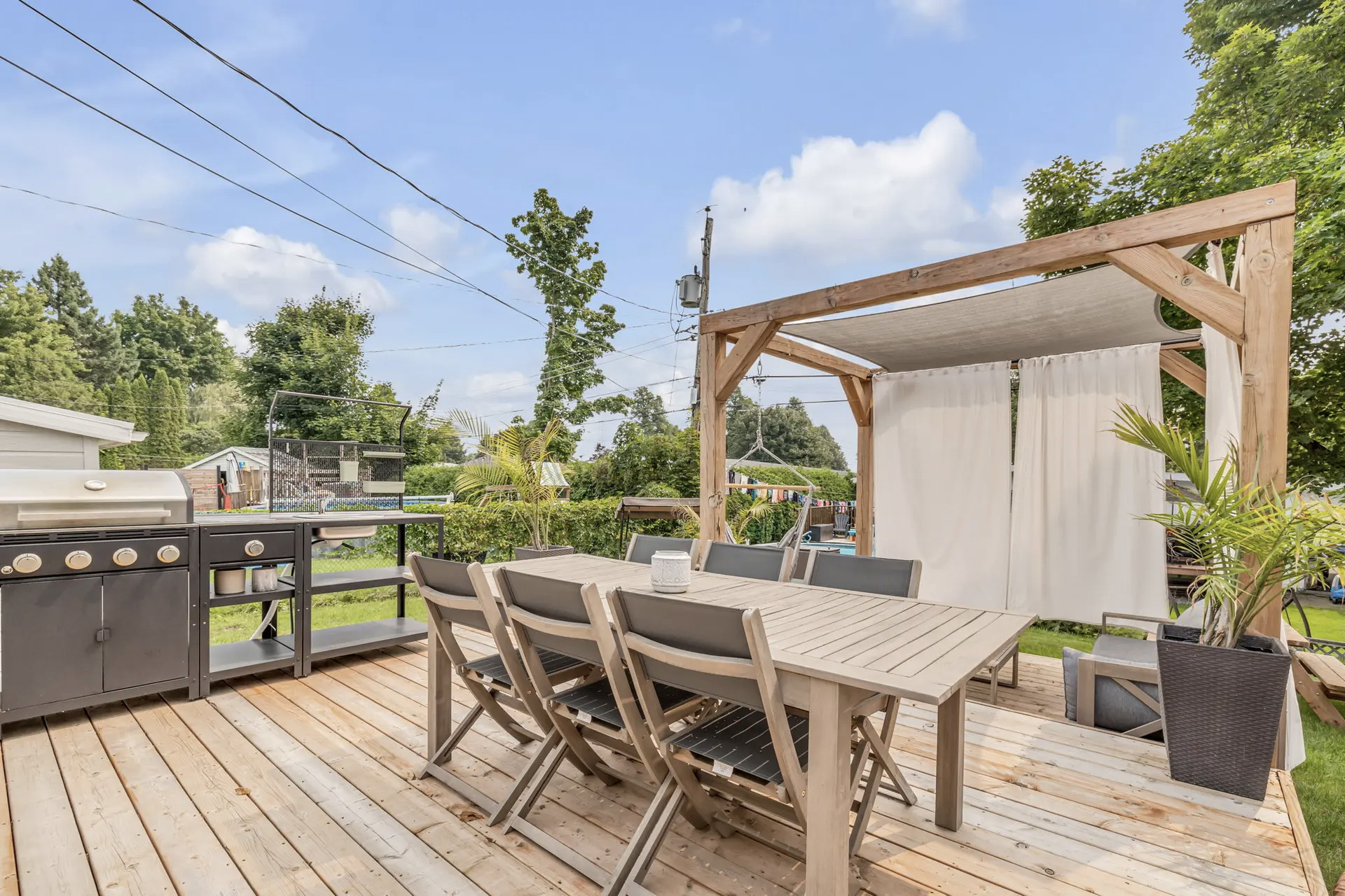 Terrasse en bois avec pergola, salle à manger extérieure et cuisine d'été équipée d'un barbecue
