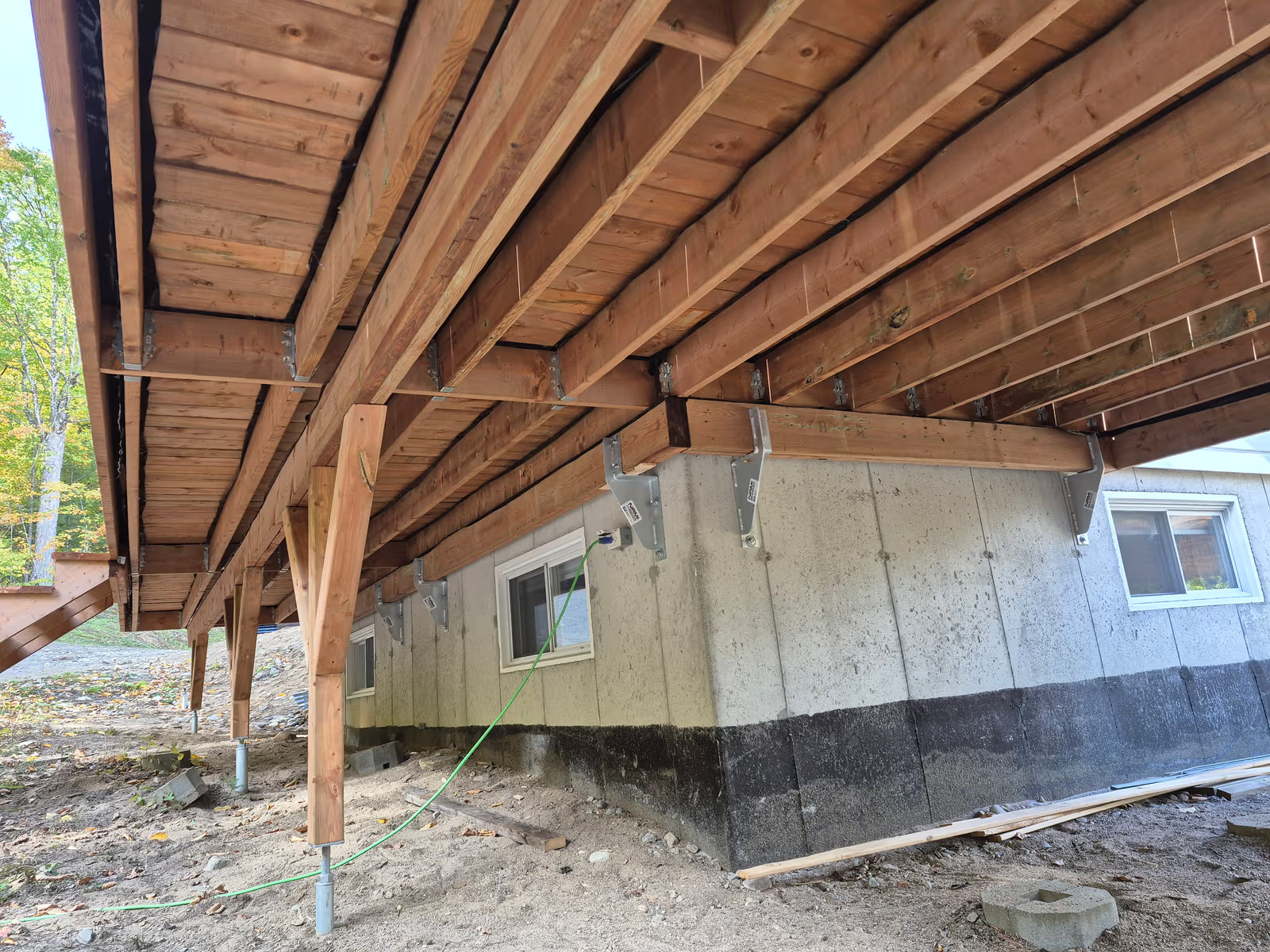 Structure de terrasse en bois surélevée avec solives, poutres et supports fixés à la fondation en béton