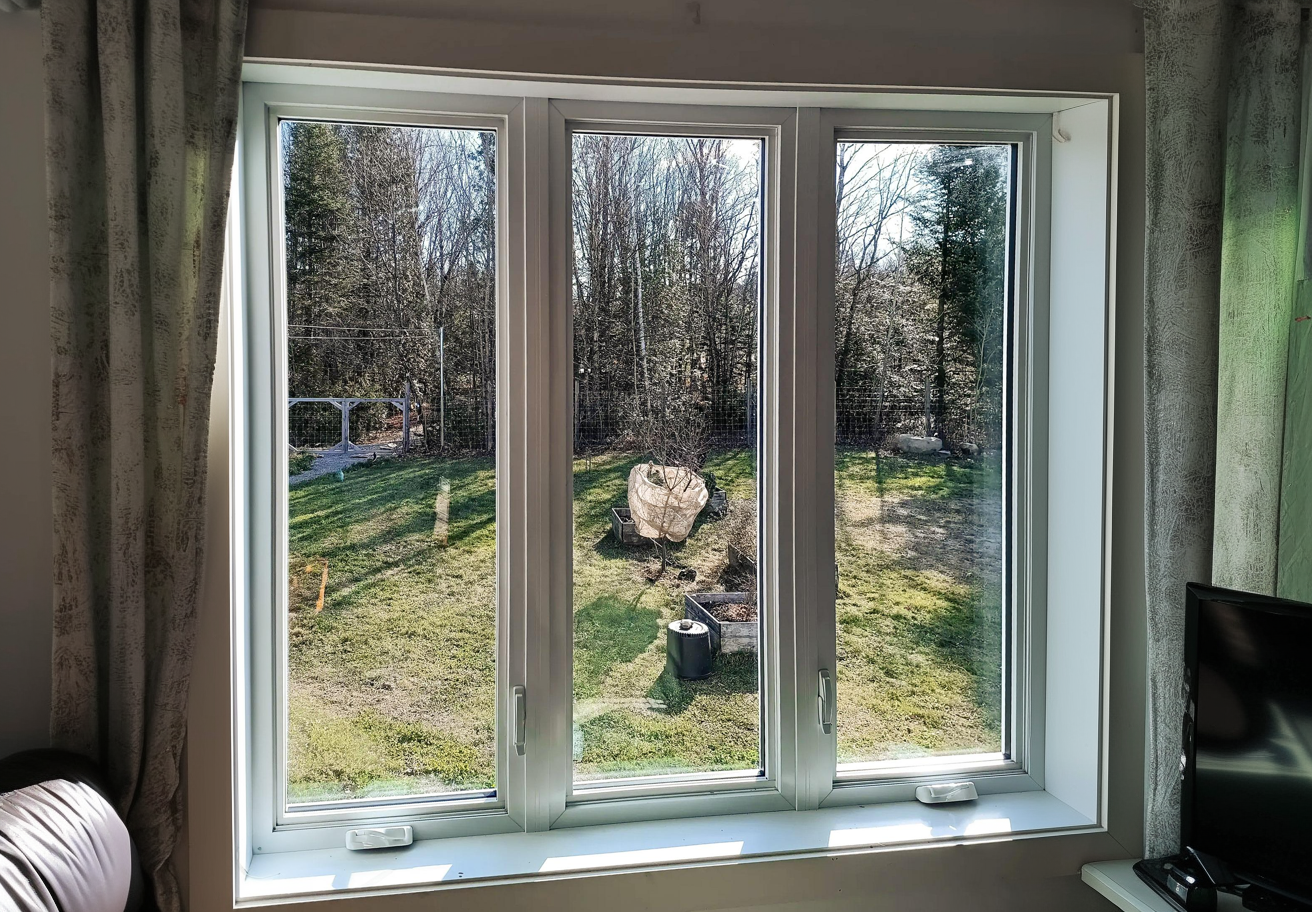 Indoor view of a garden through a triple-pane PVC window with white frame