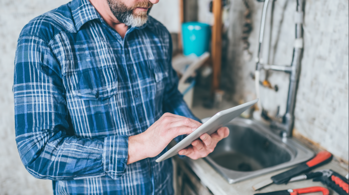 man using a tablet near a sink for inspection or repair