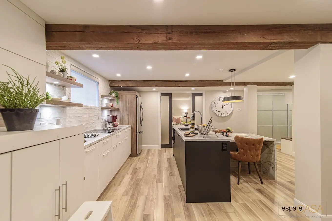 Modern kitchen with central island, wooden ceiling beams, white cabinets, recessed lighting, and wood-look flooring