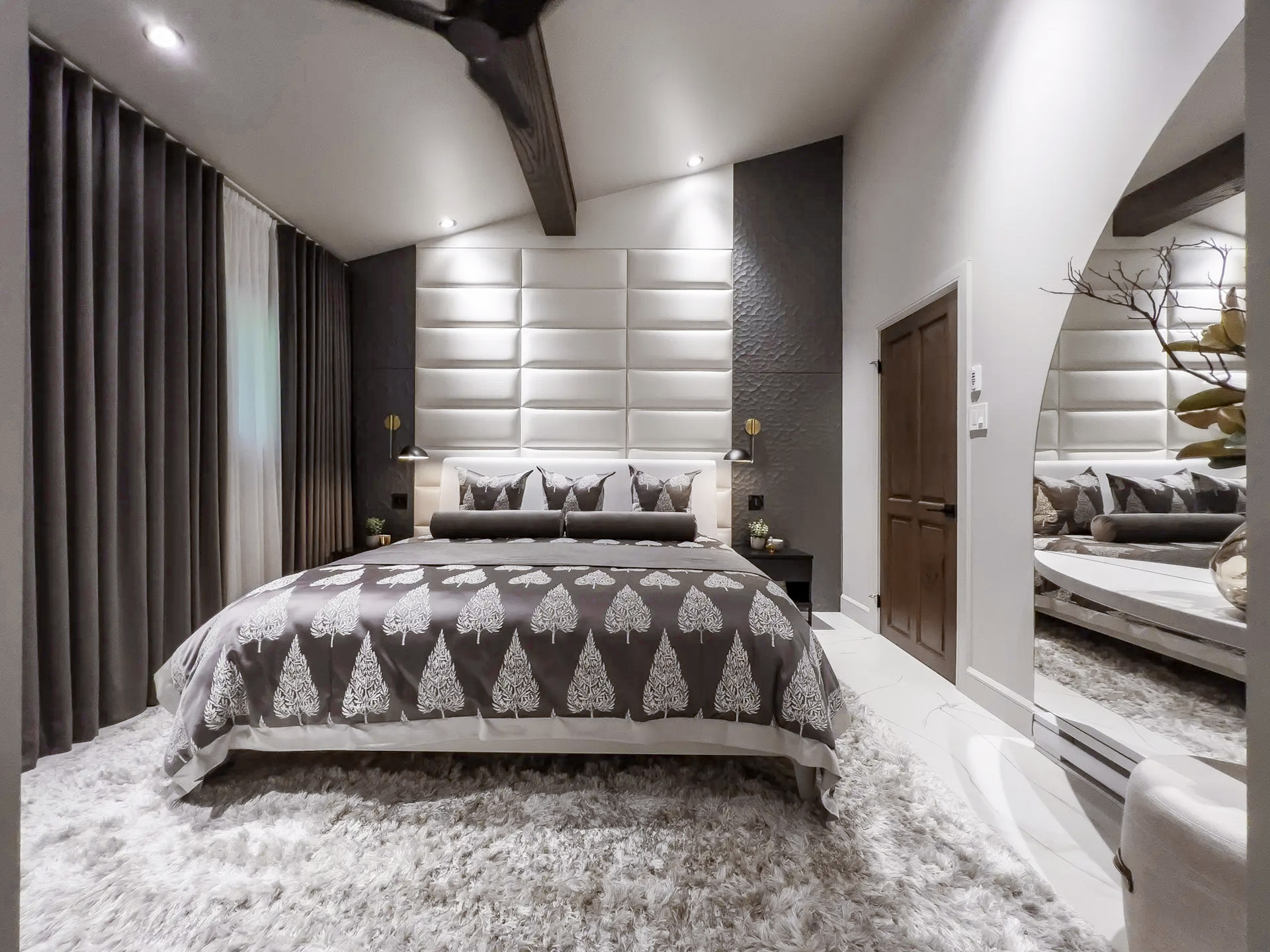 Modern and luxurious bedroom with decorative bed, plush rug, textured walls, and integrated lighting.