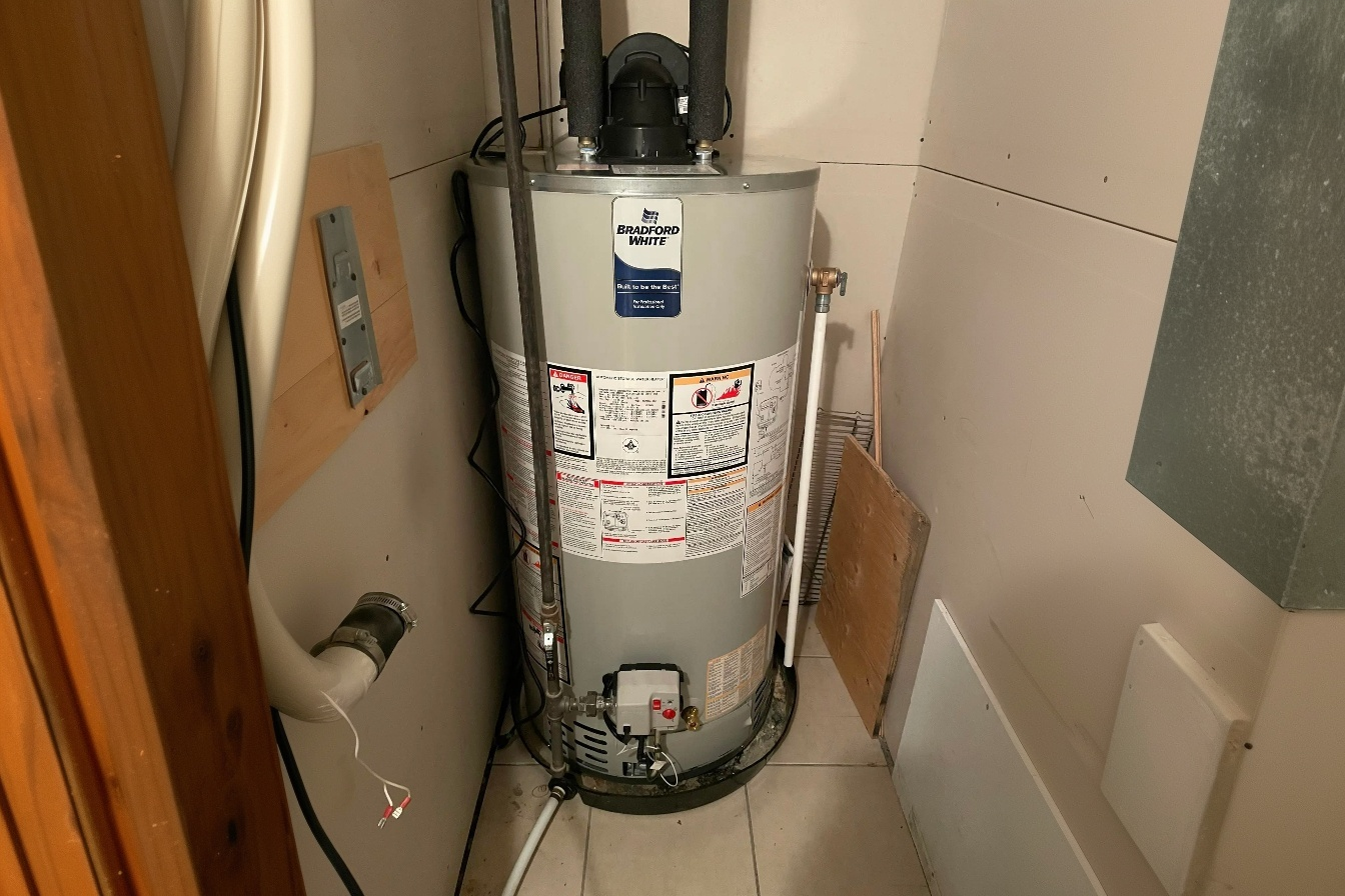 Chauffe-eau résidentiel au gaz de marque Bradford White installé dans une petite salle de service avec conduits de ventilation