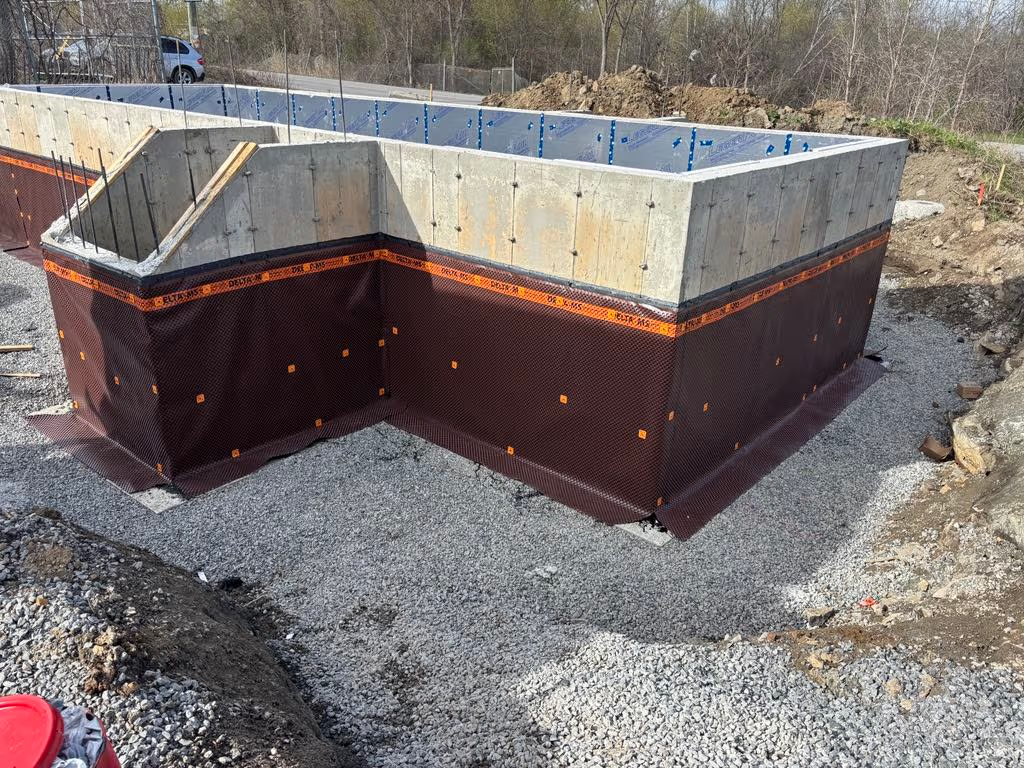 Fondation de maison en béton avec membrane d’imperméabilisation et préparation de drainage extérieur