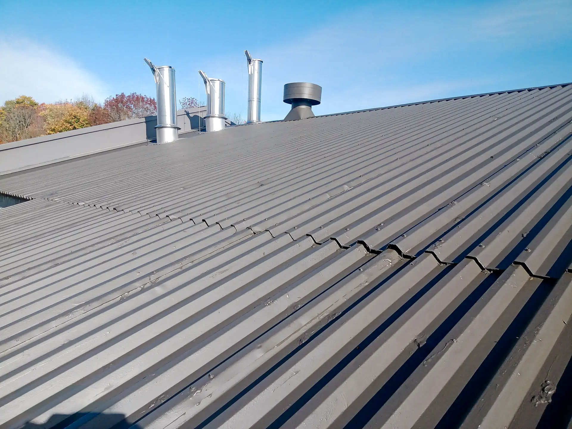 Corrugated iron roof with metal chimneys and blue sky in the background