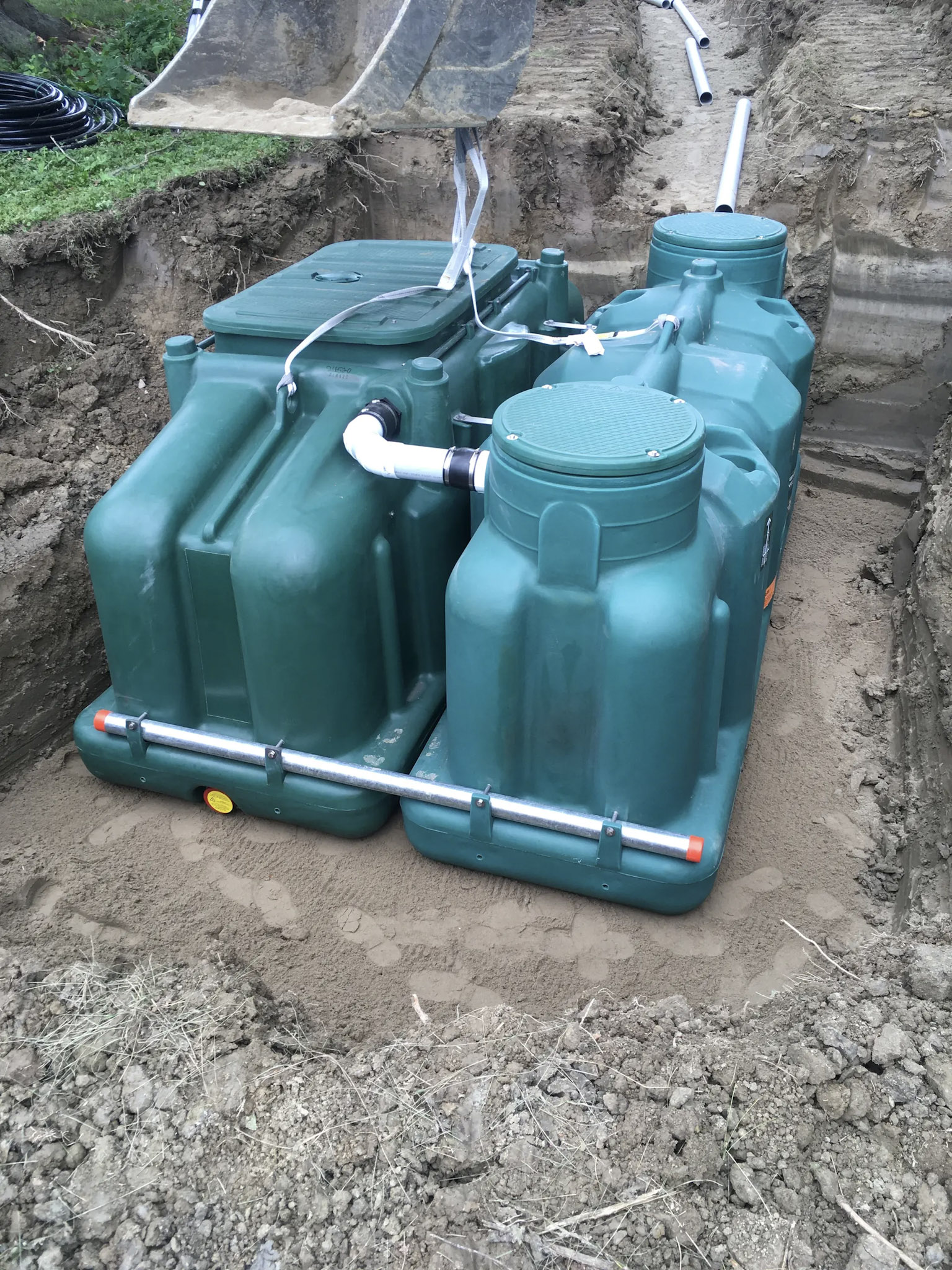 Plastic septic tank installation with pipe connections in an excavated trench.