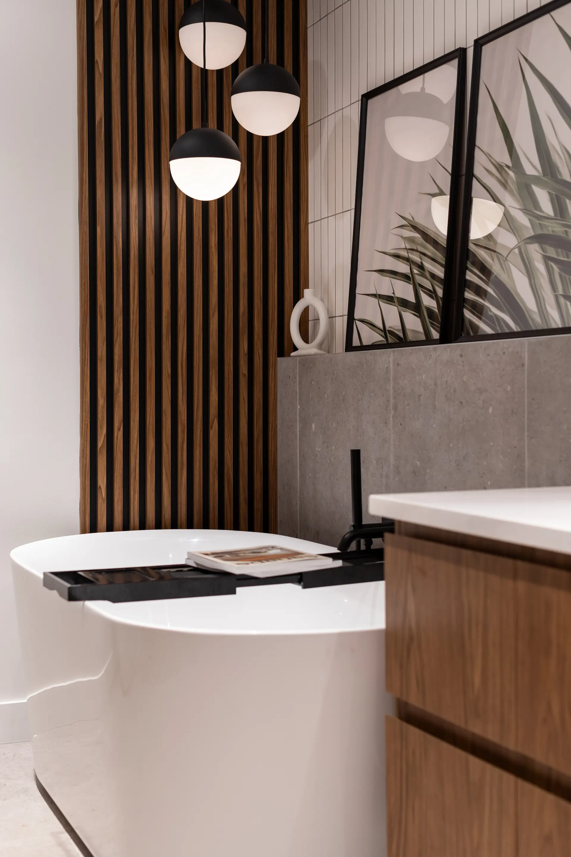 Designer bathroom with freestanding bathtub, wood slat wall and modern pendant lighting