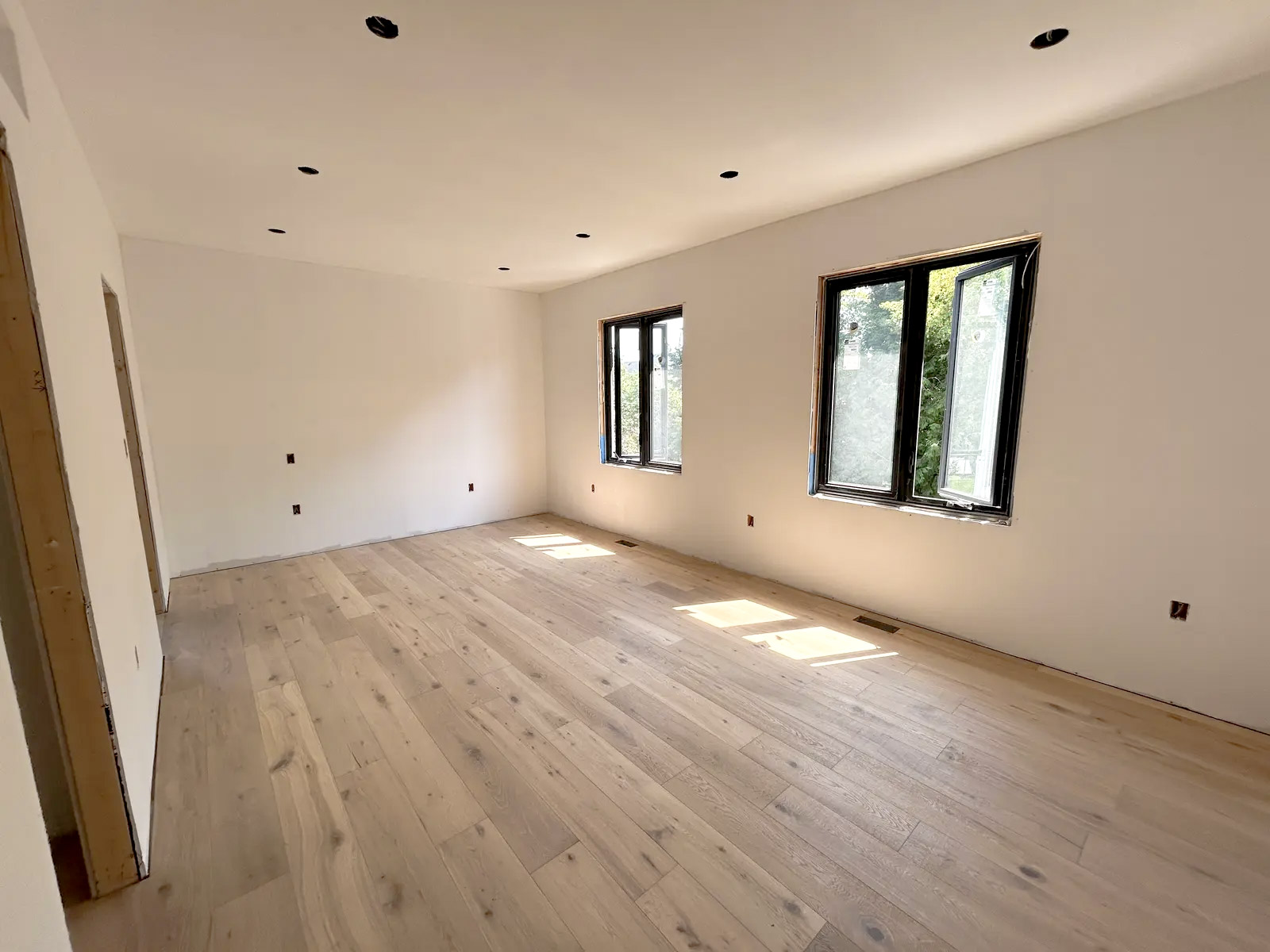 Pièce lumineuse en rénovation avec plancher de bois clair et murs fraîchement peints en blanc