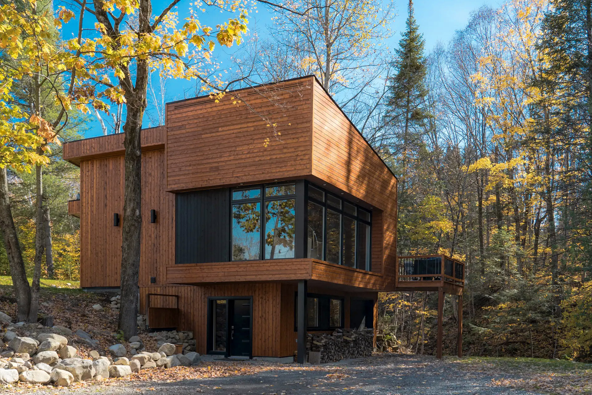 Modern wood fiber house in an autumn forest with large windows and a terrace on stilts