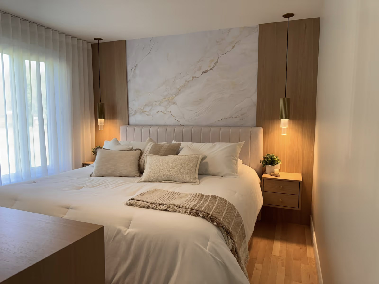 Modern room with white bed, marble effect wall, wooden panels and hanging lights