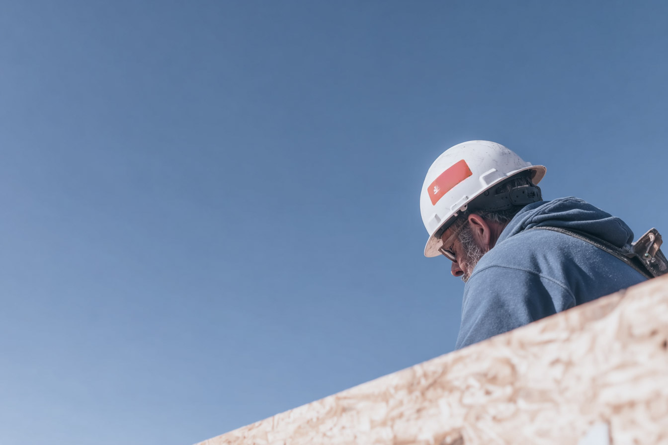 Construction worker wearing a white safety helmet on a construction site under a clear sky