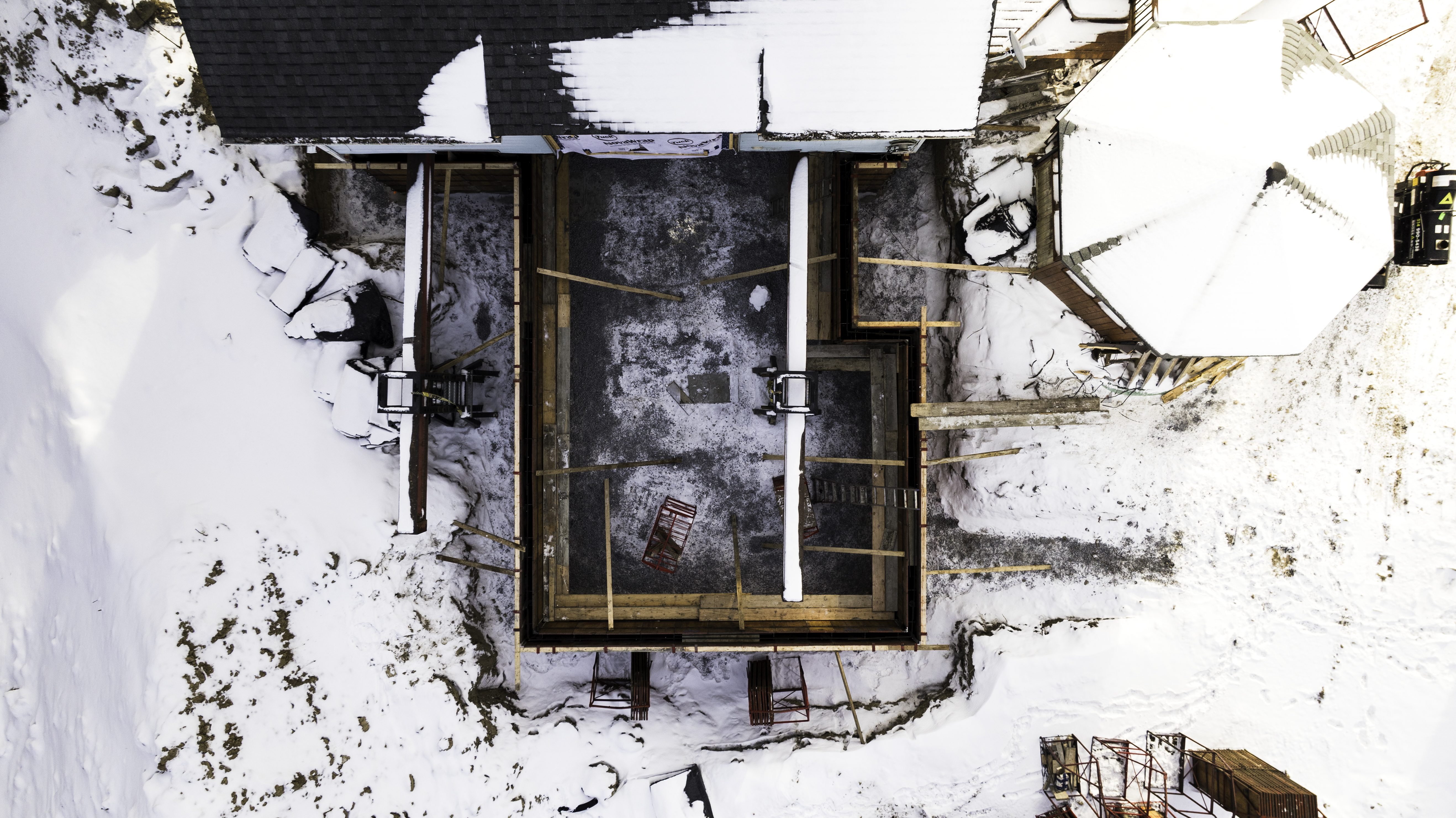 Vue aérienne d'un chantier de construction en hiver avec fondations en cours de réalisation.