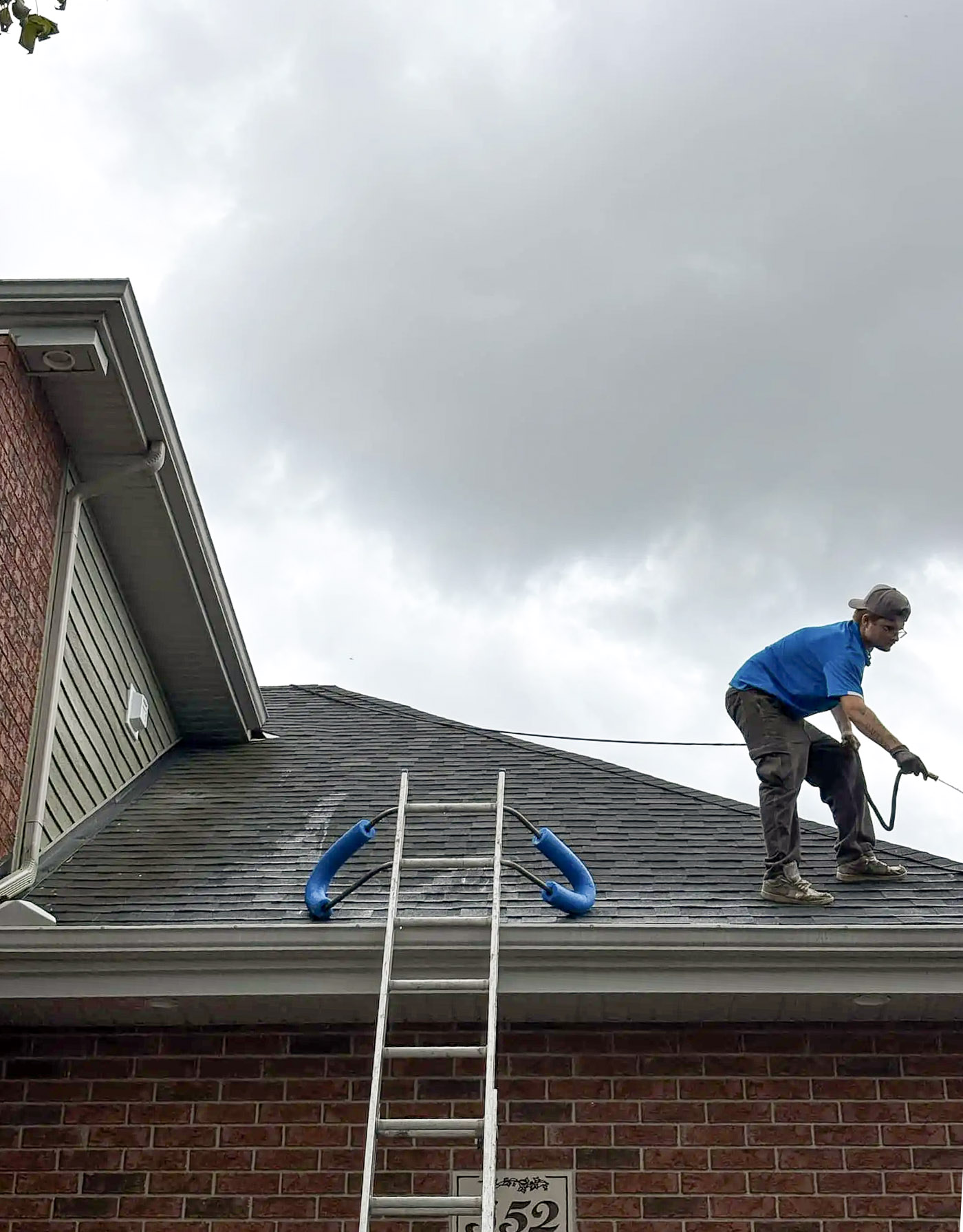 Residential roof cleaning by a worker using a high-pressure jet