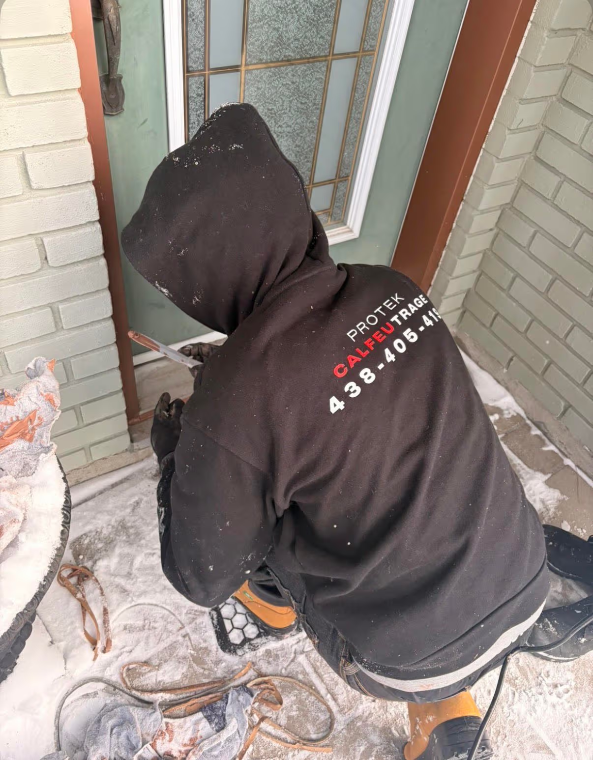 Caulking technician working around a glass exterior door in winter