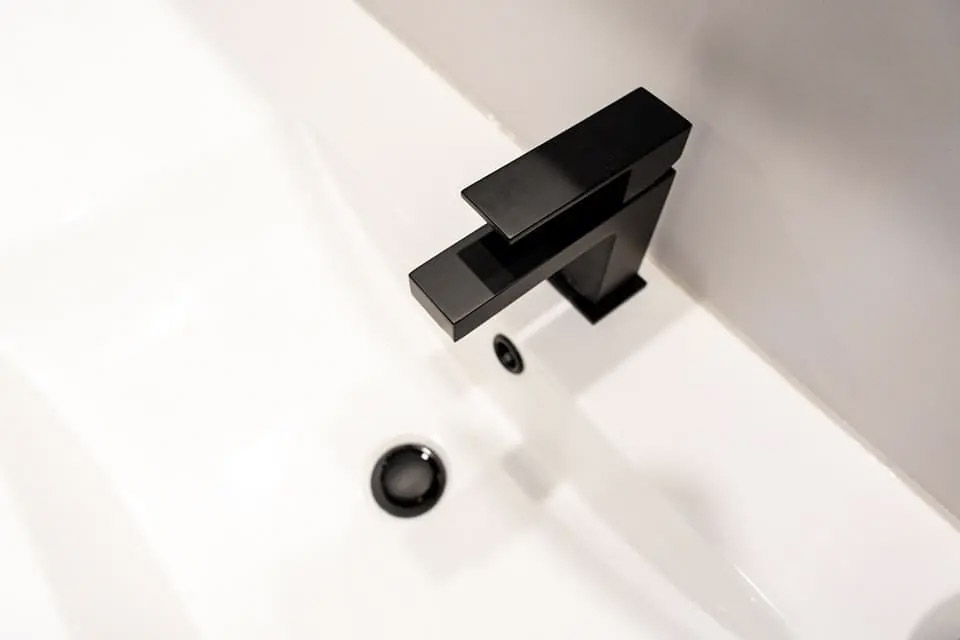 Robinet noir mat moderne installé sur un lavabo blanc épuré.