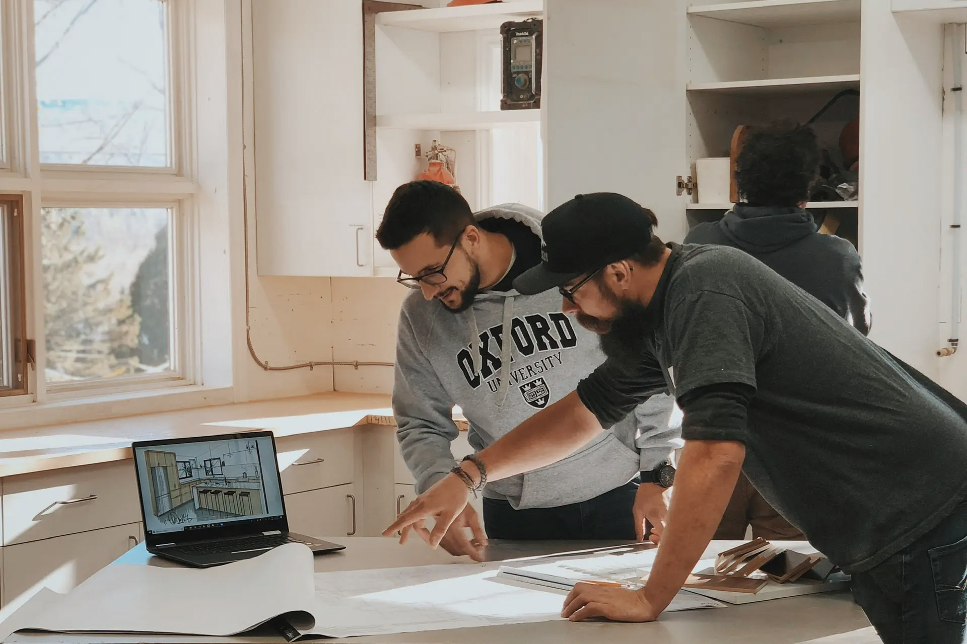 Professionals collaborating in a workshop on an architectural project design with plans and a laptop.