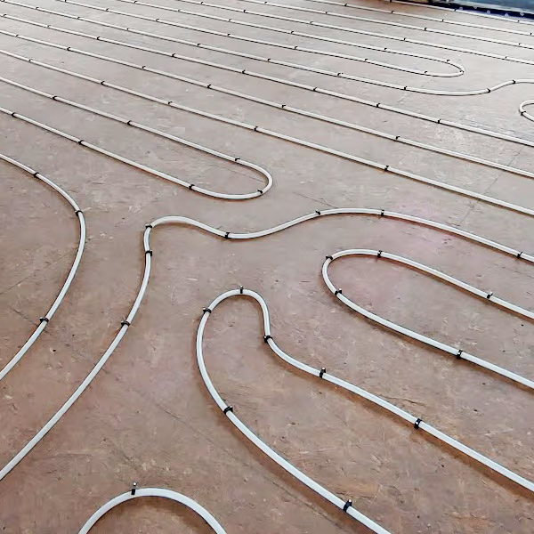 Installation de tuyaux de chauffage radiant hydronique fixés sur un sous-plancher avant la pose du revêtement de sol.