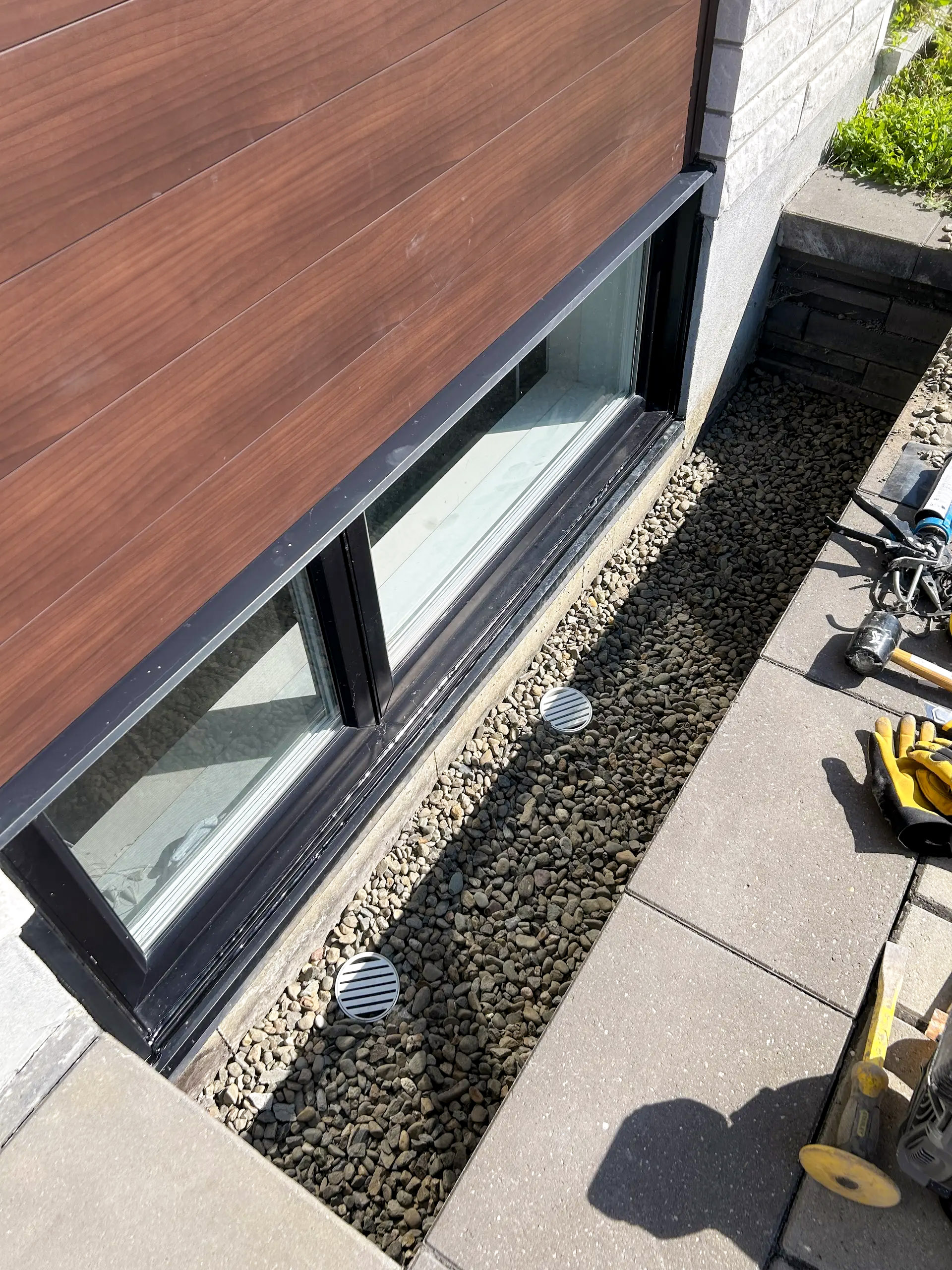 Window sill with gravel drainage and protective grilles installed at basement floor level