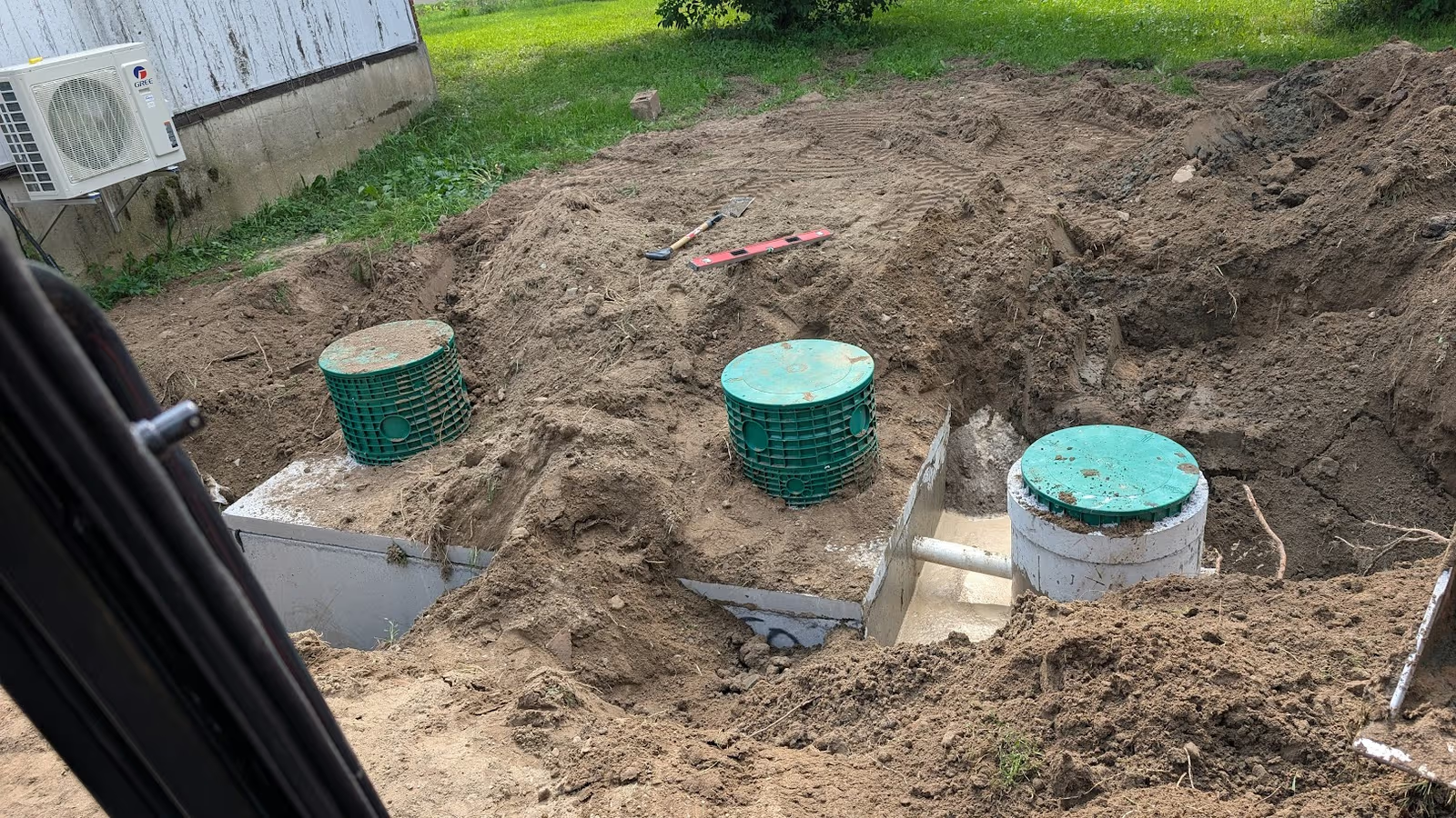 Installation de fosse septique avec excavation, regards d’accès et tuyaux souterrains près d’une maison résidentielle