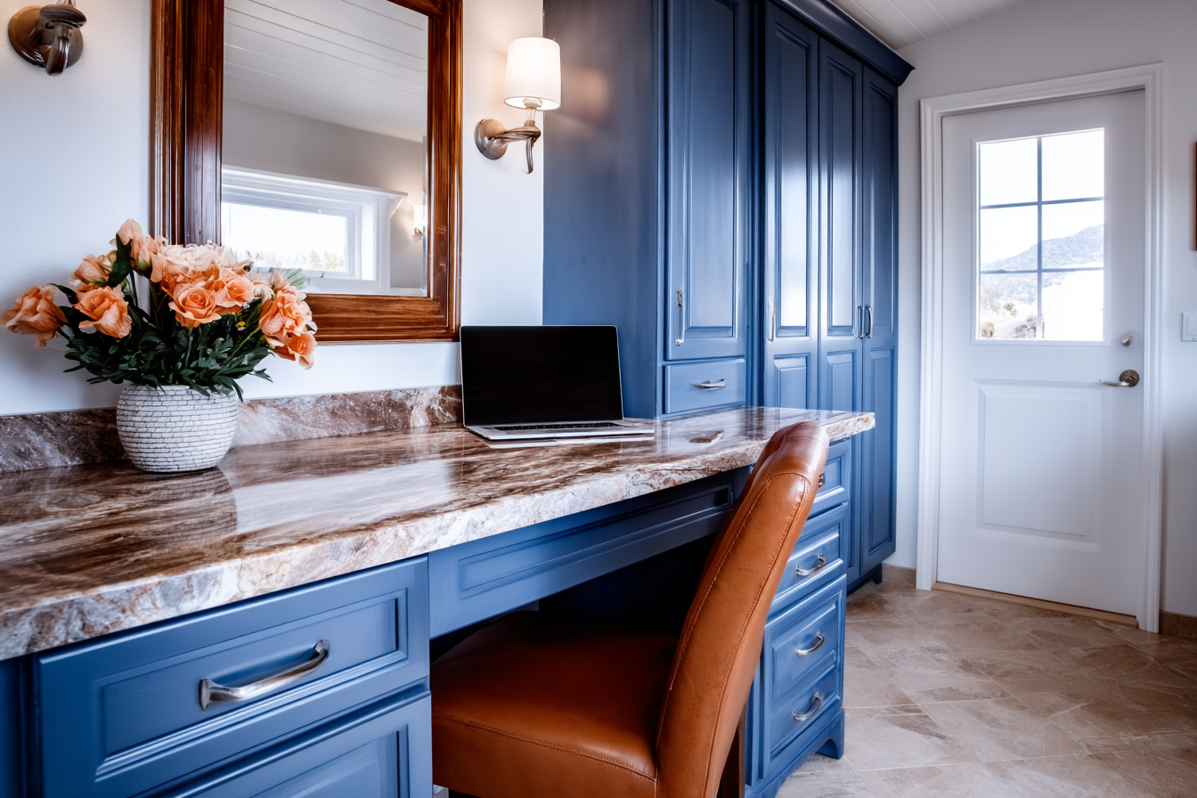 Home office with custom blue cabinets, marble-look countertop, leather chair and laptop
