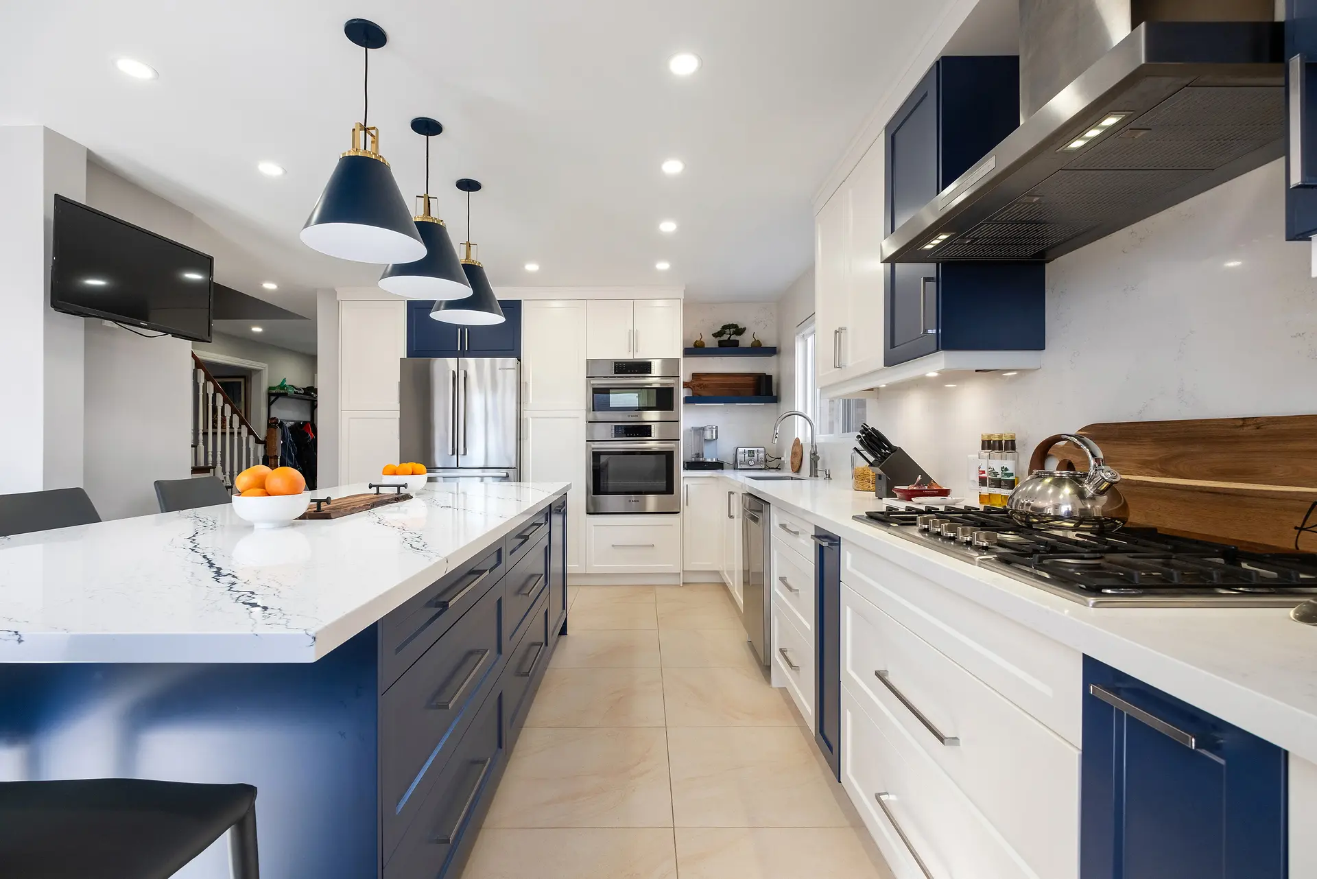 Modern kitchen with navy and white cabinets, quartz island, and built-in appliances